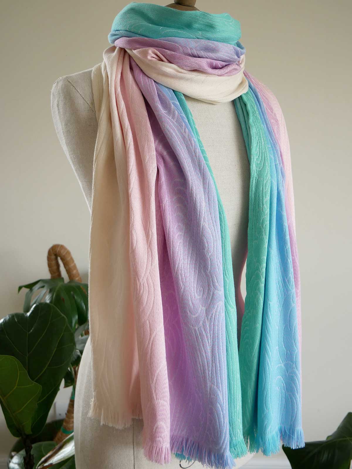 Pastel colored scarf on a mannequin with a plant in the background