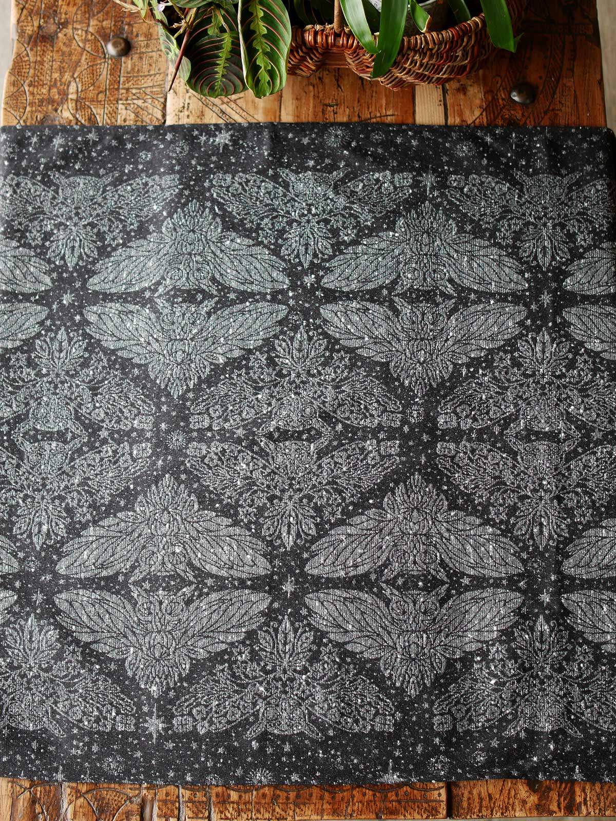 Black fabric with sliver owls and stars, laid on a wooden table.