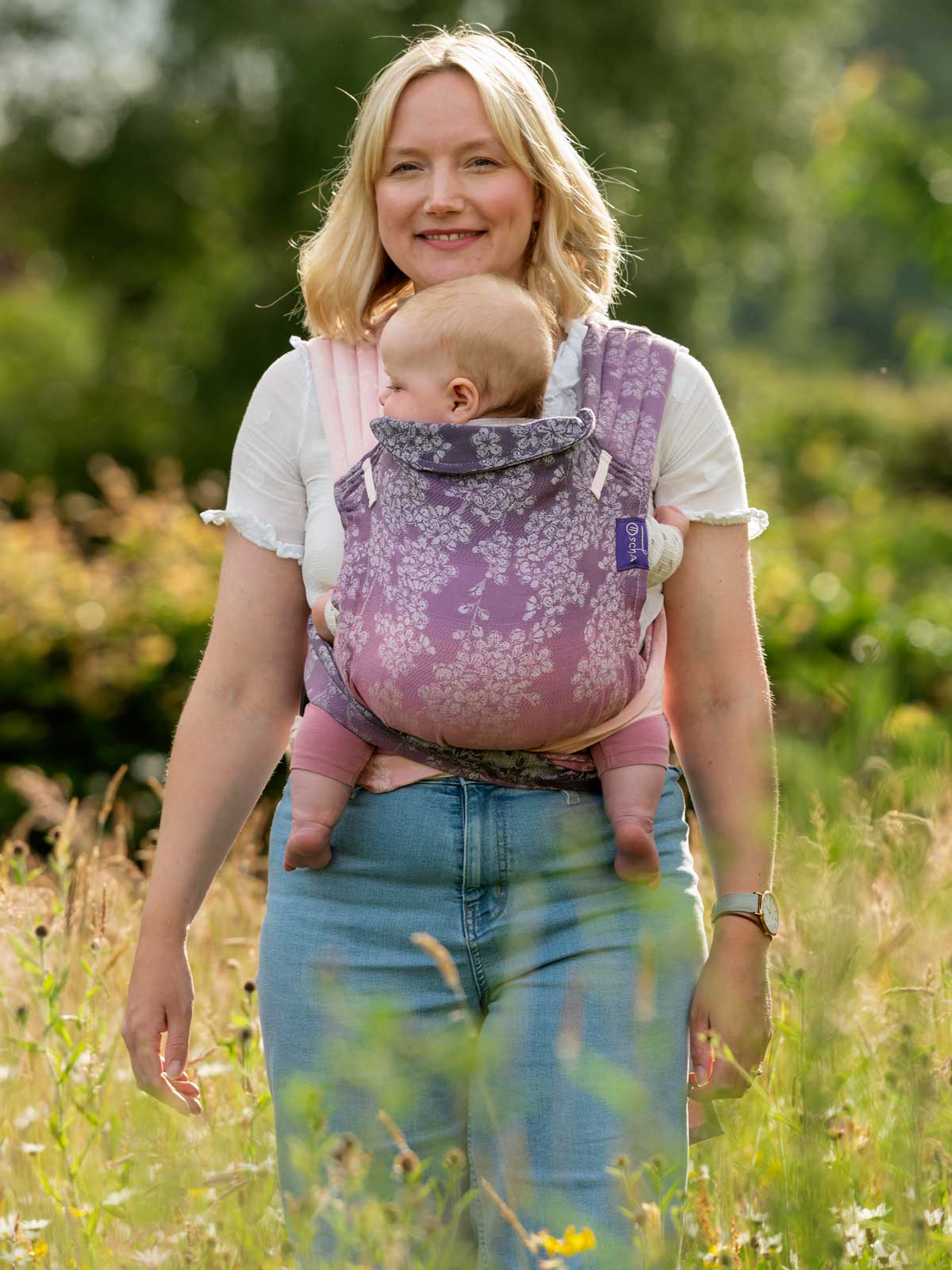 Model wearing baby in Cairis blossom pattern carrier.