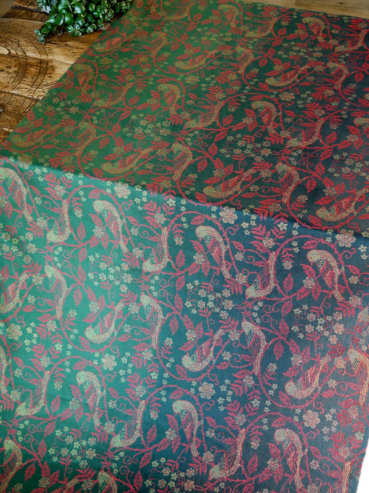 Patterned cloths with red and green designs on a wooden surface.