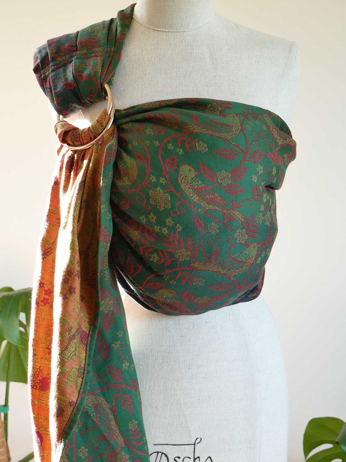 Green patterned Briarwood Winter's Song Ring Sling on a mannequin with a white background
