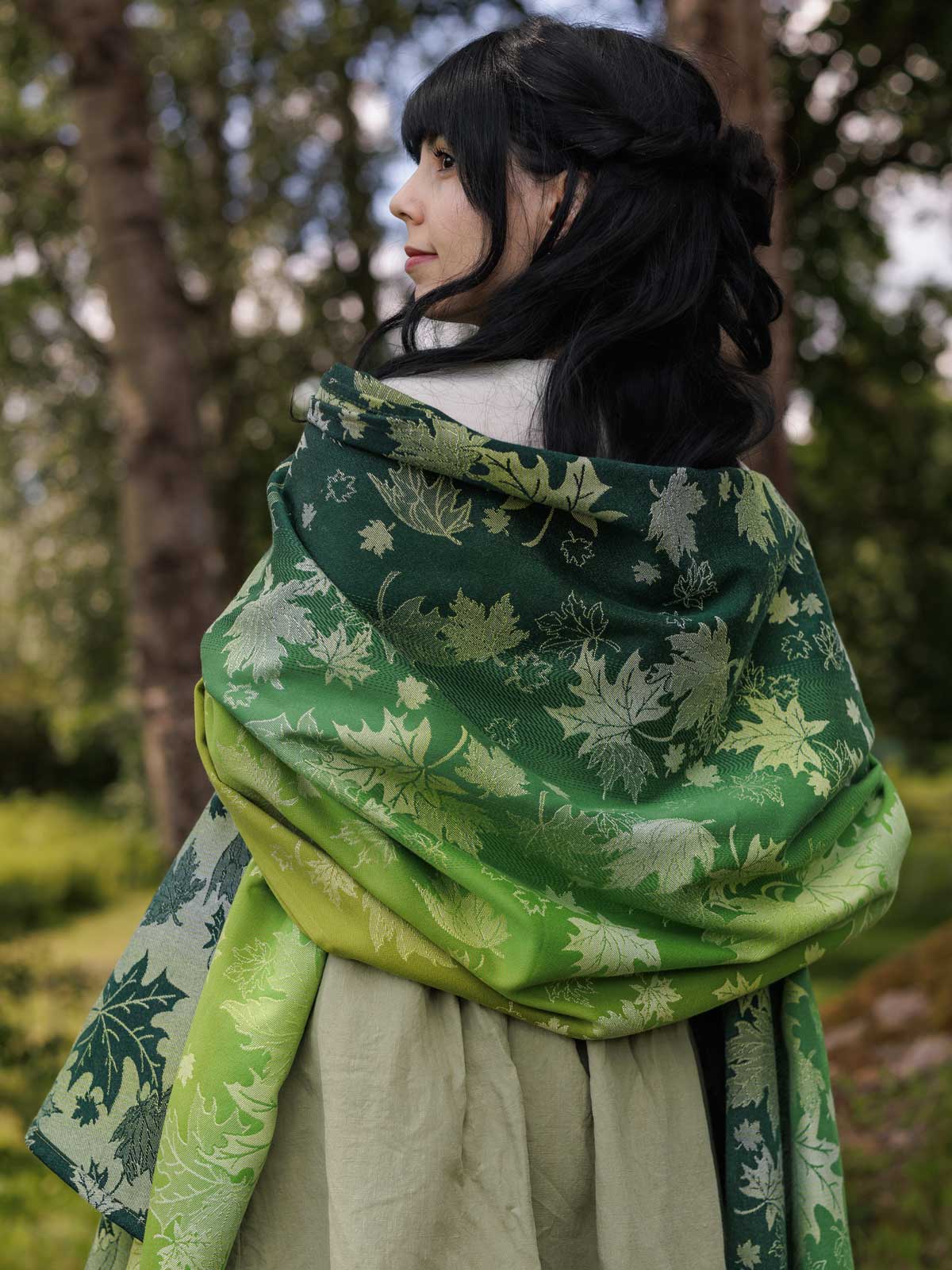 The back of a woman wearing a green shawl with a leaf pattern.