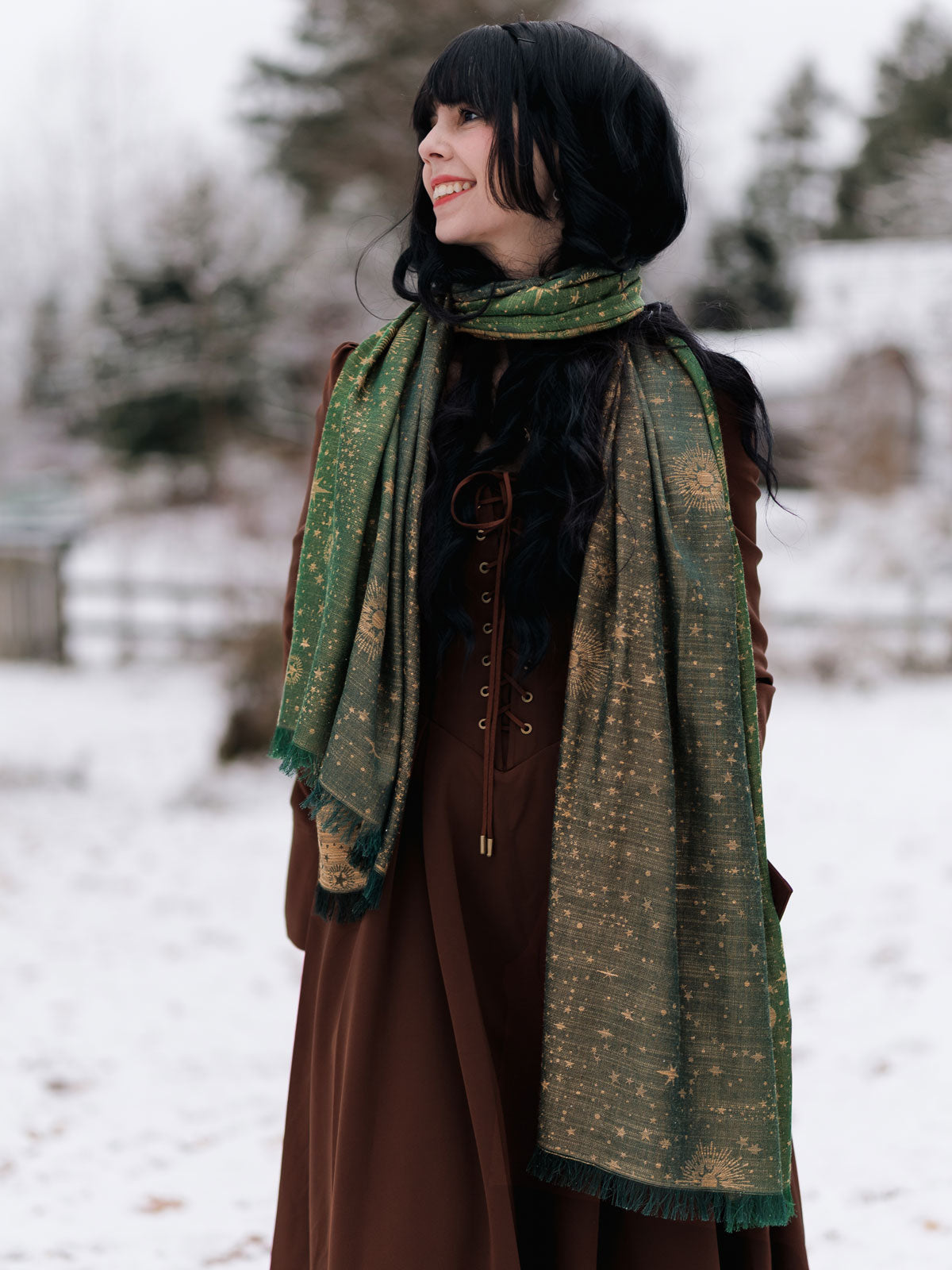 Person wearing a long brown coat and green patterned scarf in a snowy landscape