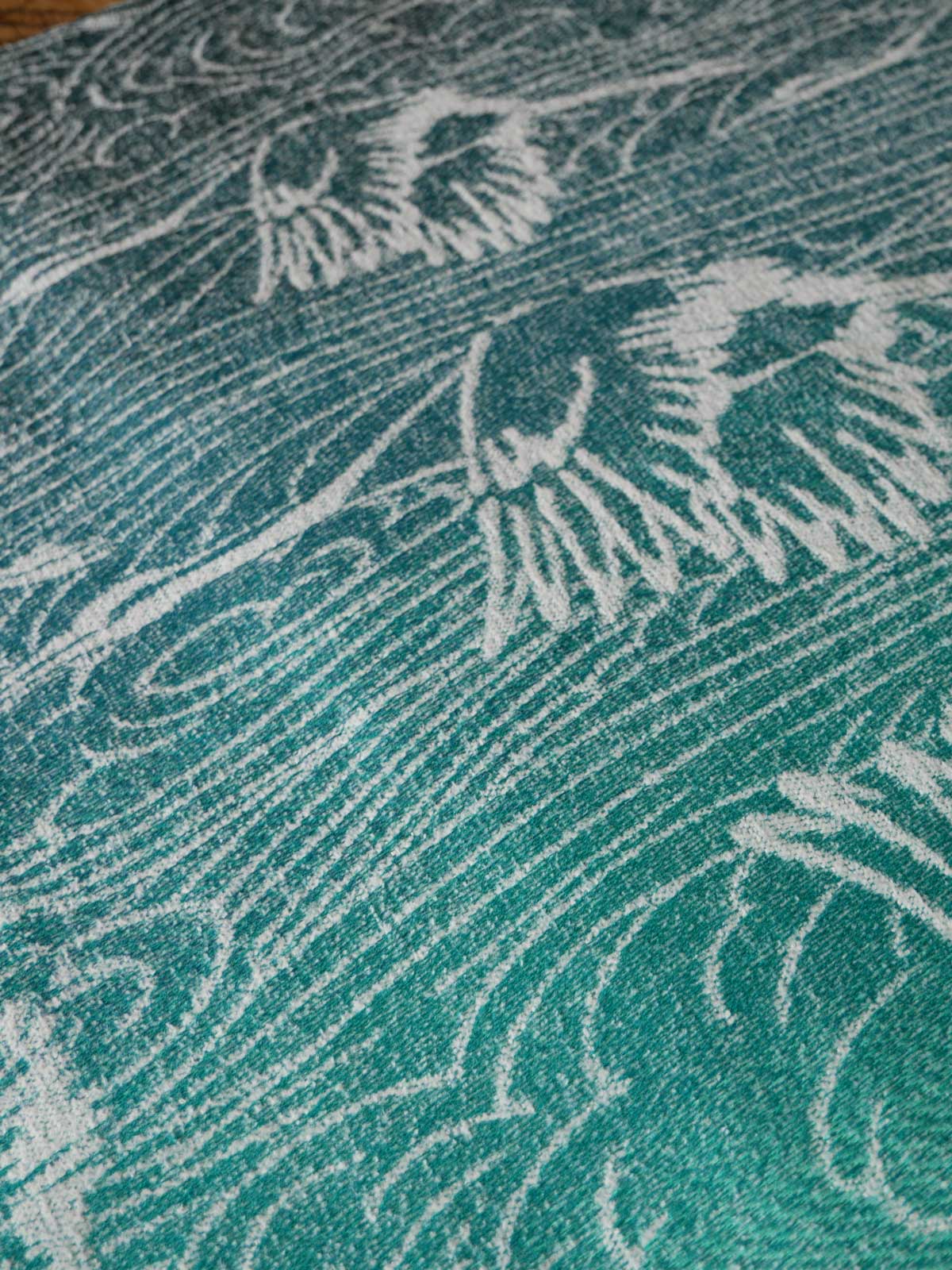 Close-up of a textured teal fabric with white crane patterns