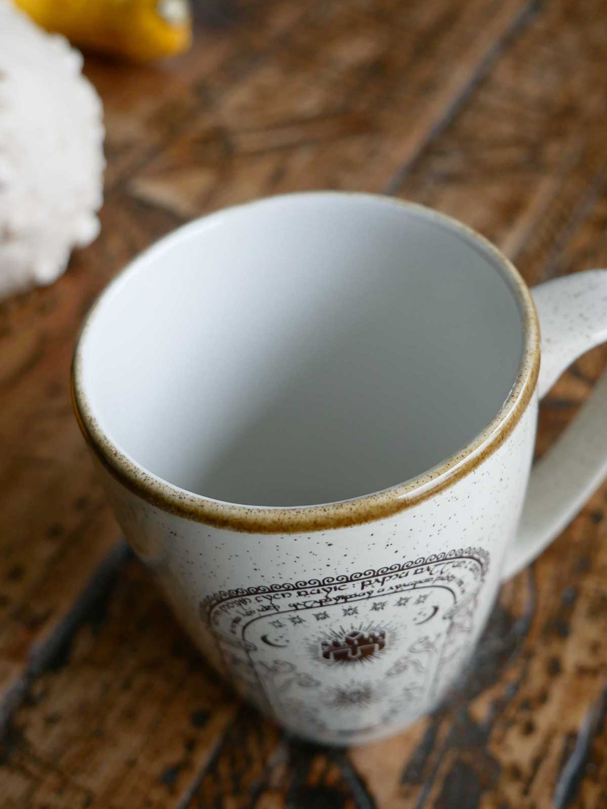 Close-up of a ceramic mug with a decorative rim on a wooden surface