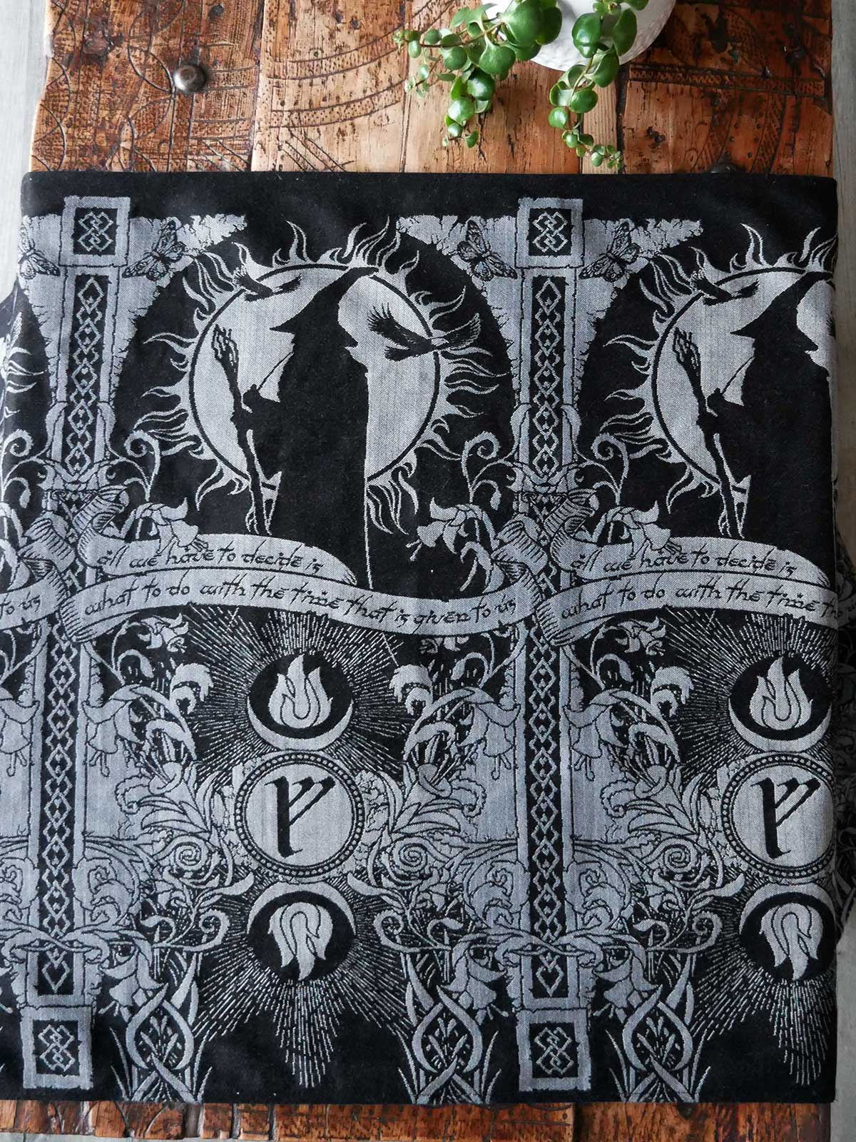 Black and silver patterned fabric with Gandalf design on a wooden surface