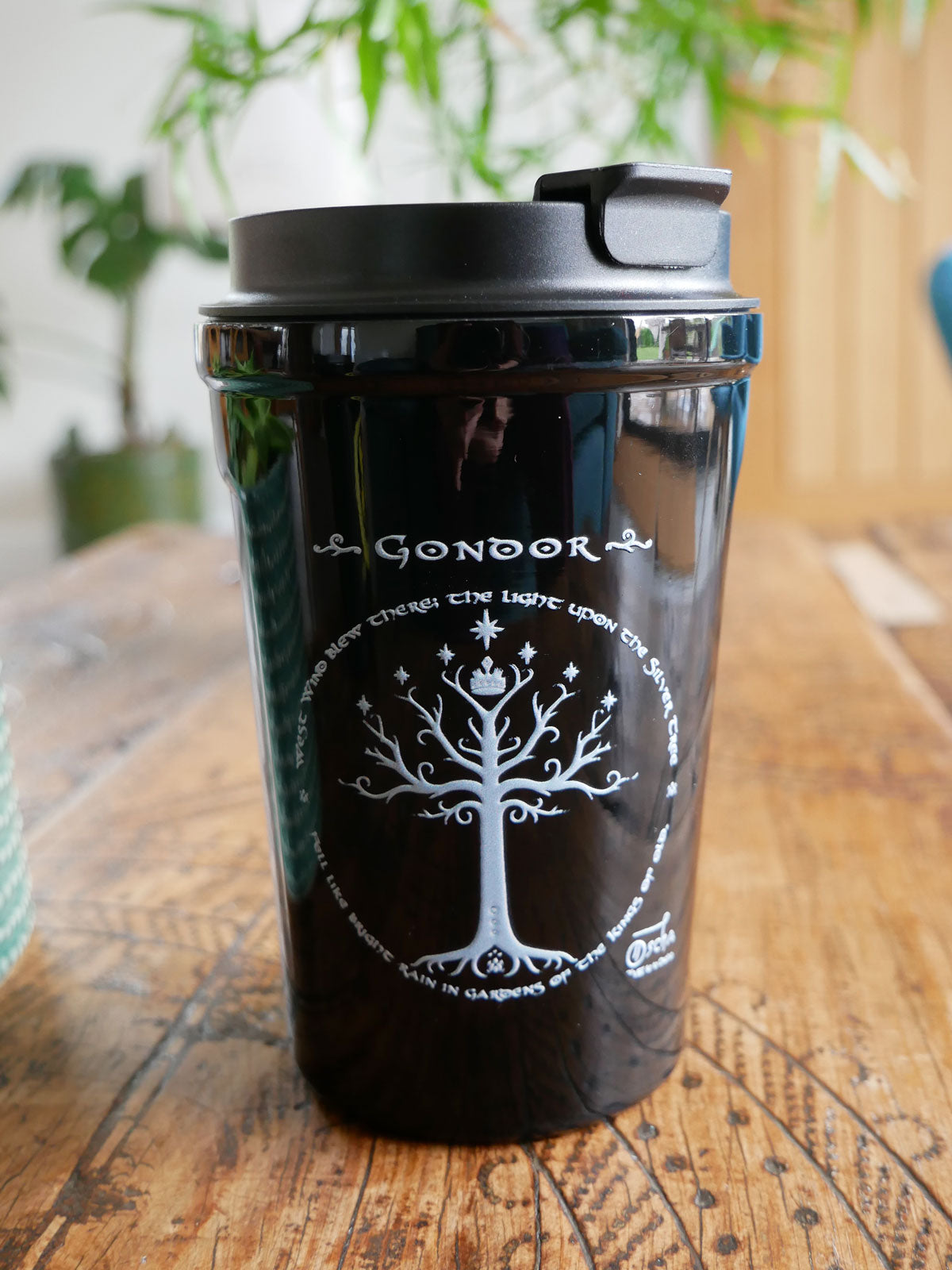 Black Gondor Travel Mug with white design on a wooden surface