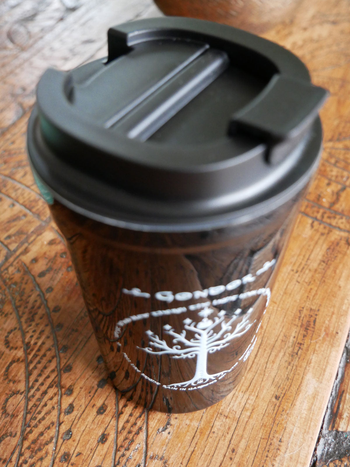 Coffee cup with a black lid on a wooden surface