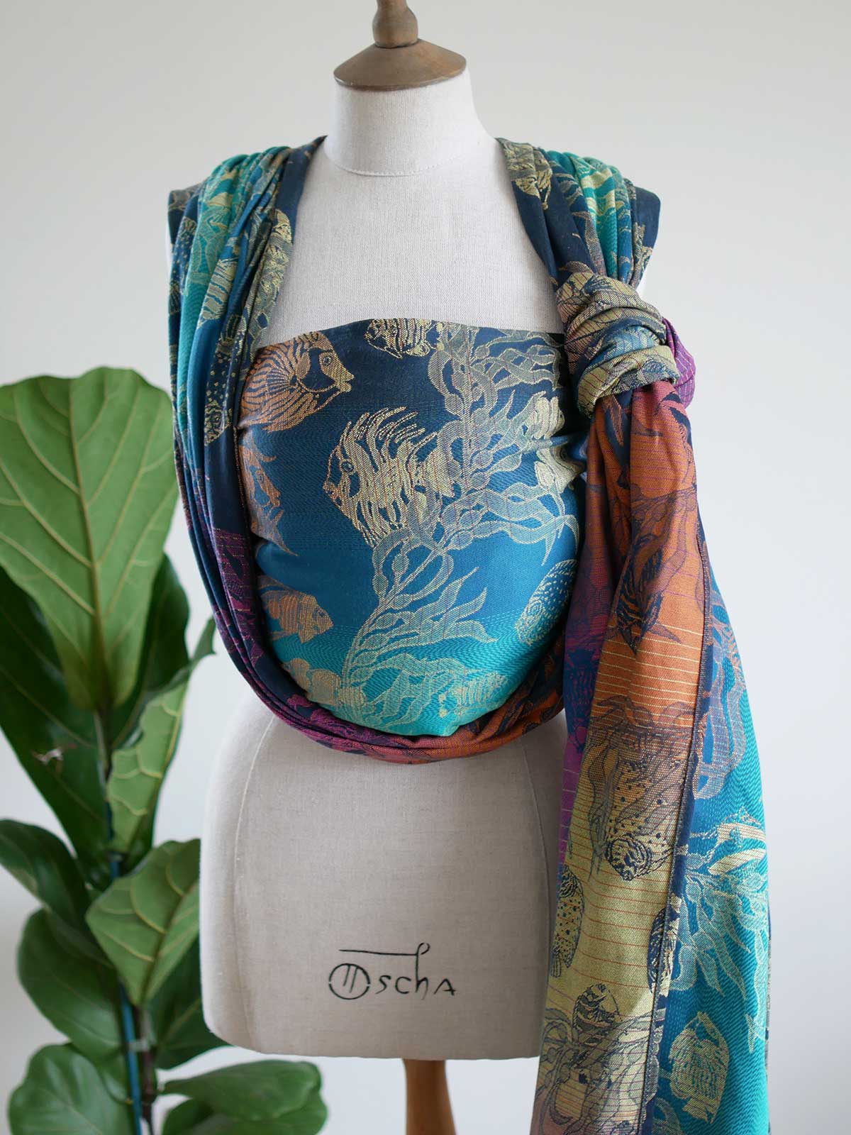 A blue teal woven wrap with tropical fish patten on a mannequin