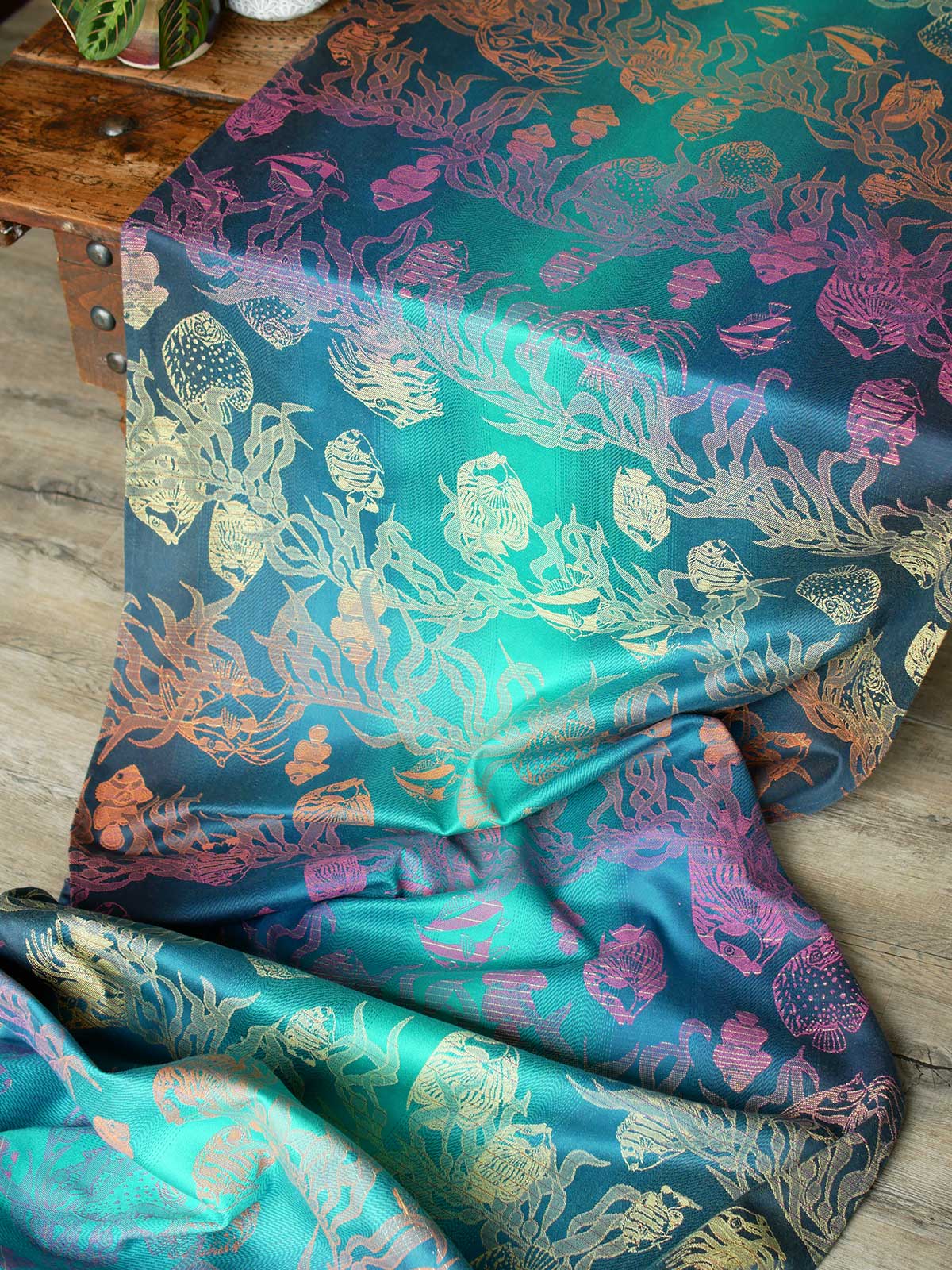 A blue teal woven wrap with tropical fish patten in gold, orange and pink