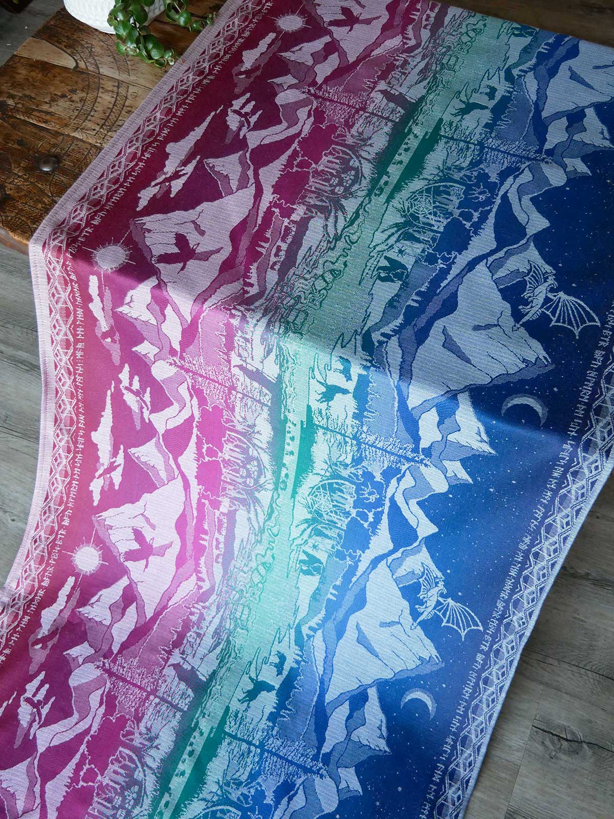 Colorful jewel toned fabric with Lord of the Rings pattern on a wooden surface