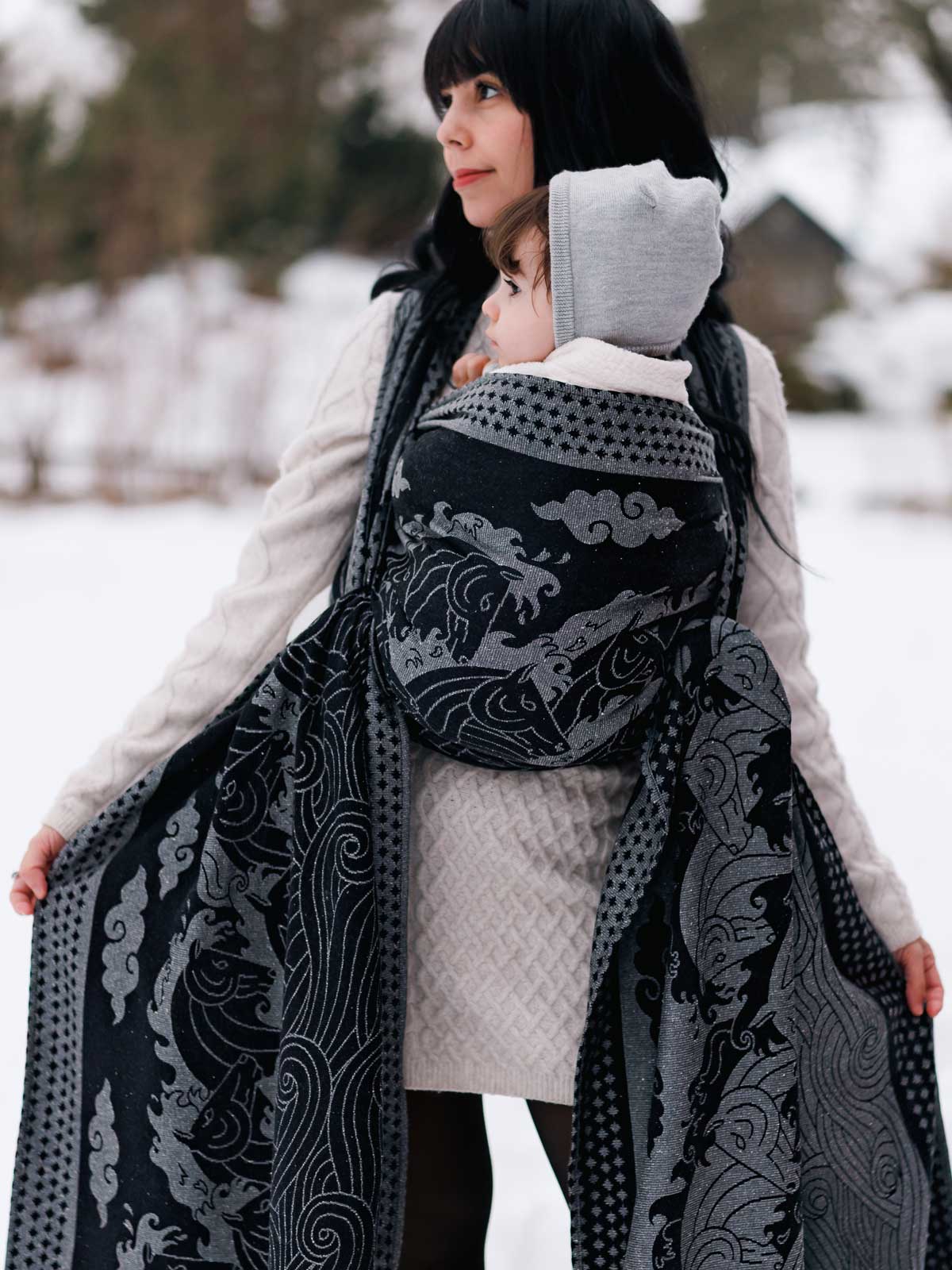 Woman holding a baby in Kelpies Stormy Seas Baby Wrap outdoors in winter