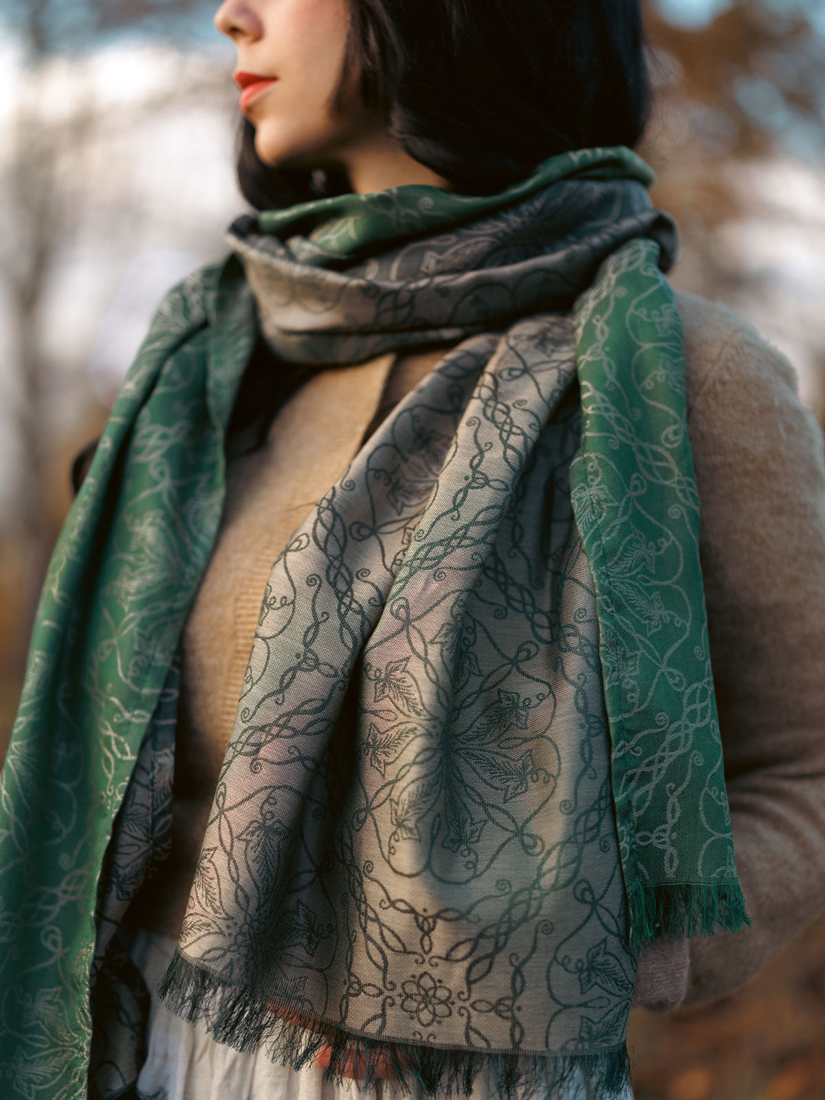 Person wearing a green patterned scarf in a blurred natural setting