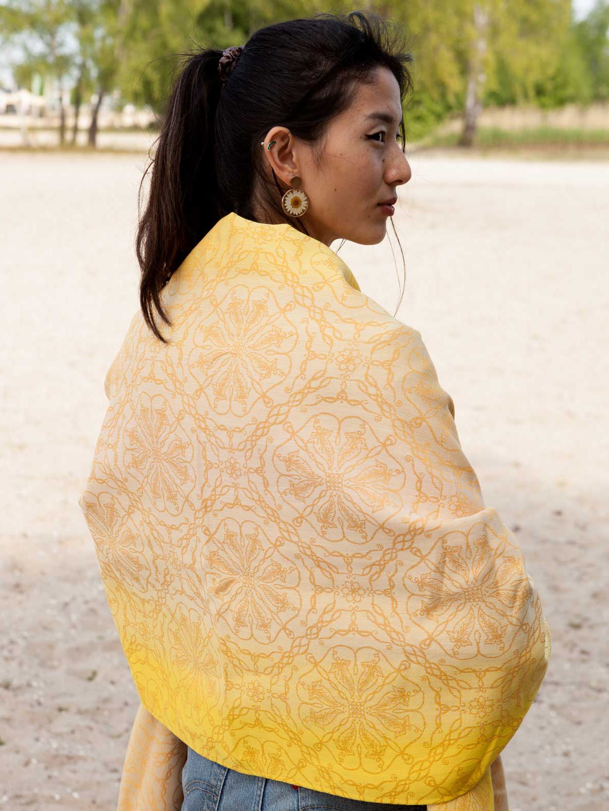 Model wearing a shawl in lemon yellow and warm patterned fabric.