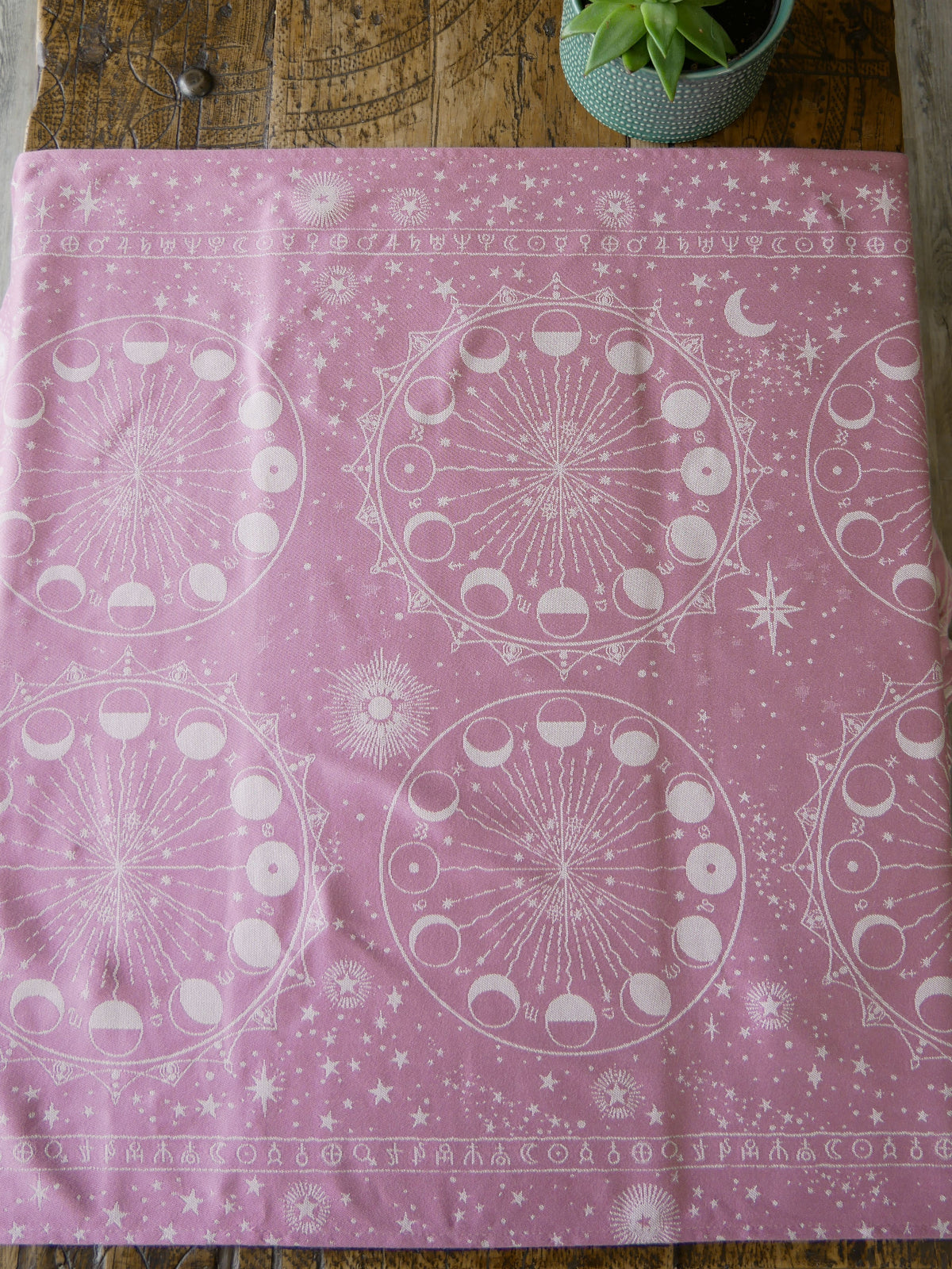 Pink fabric with white celestial pattern on a wooden surface