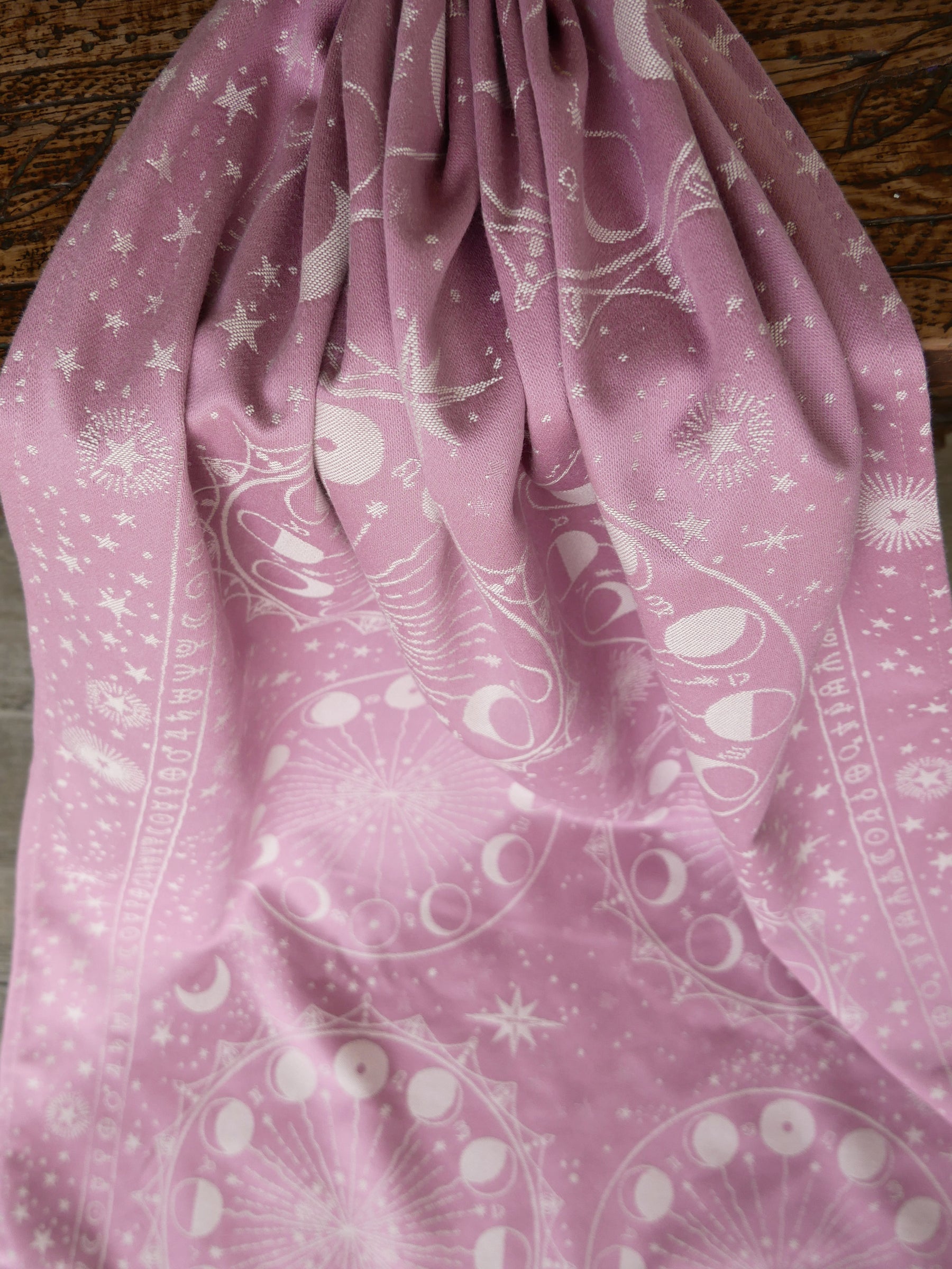 Pink fabric with white lunar patterns on a wooden surface