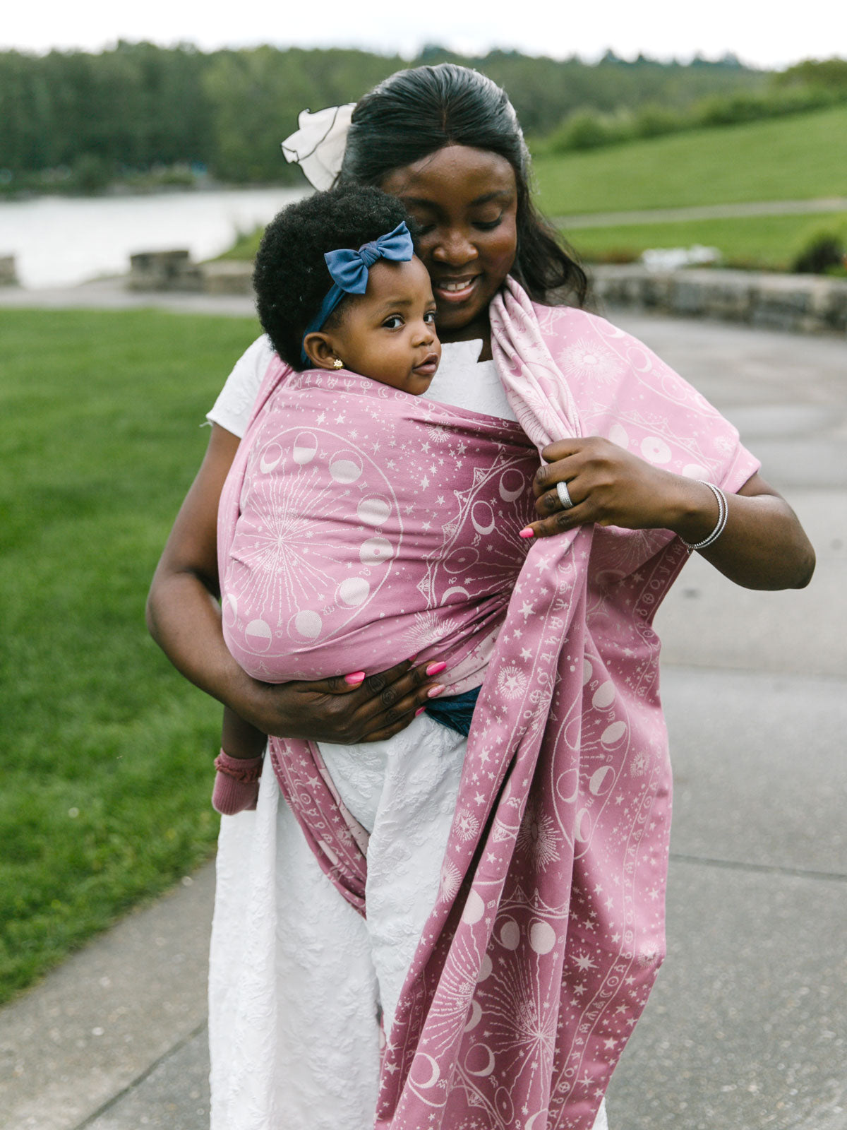 Woman wrapping a child in a pink Lunae Isla Baby Wrap.
