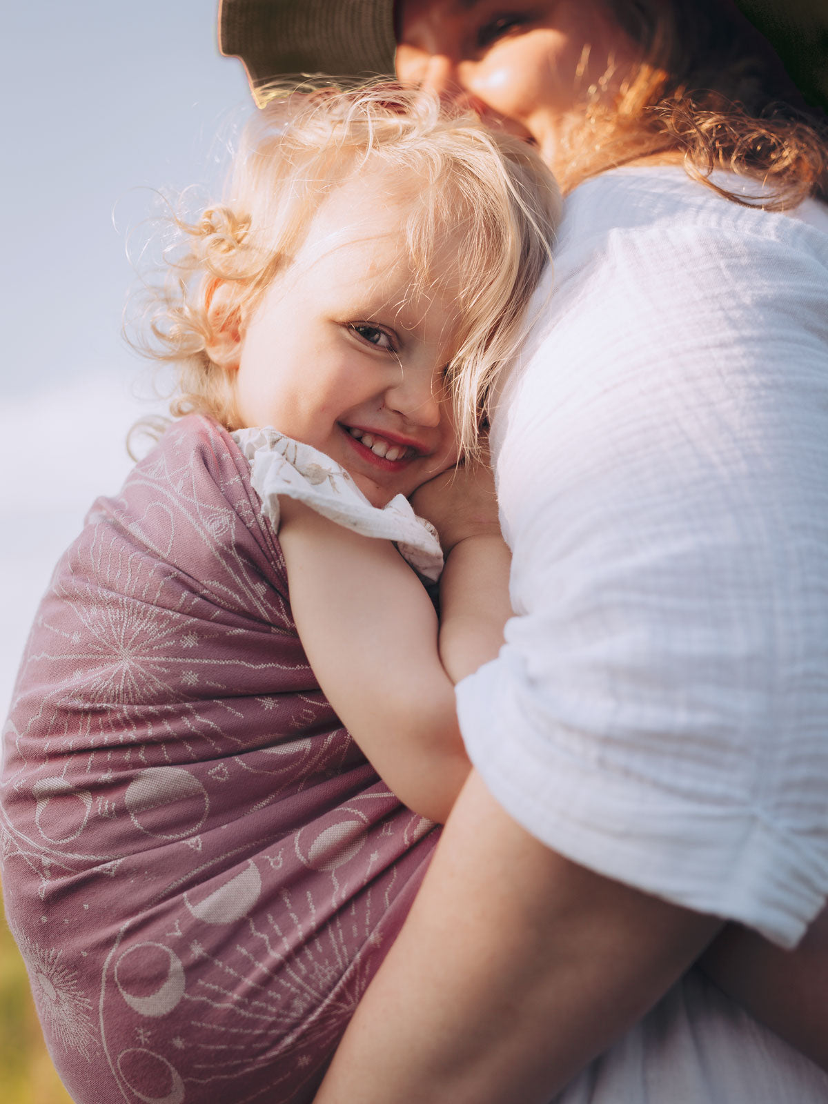 Woman holding a child in a sling with a blurred background