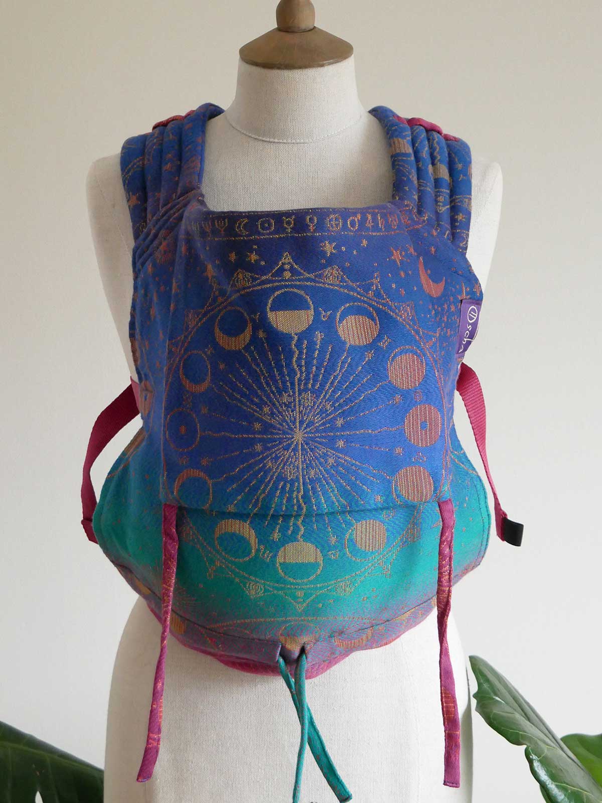 Colourful baby carrier with celestial design on a mannequin against a white background