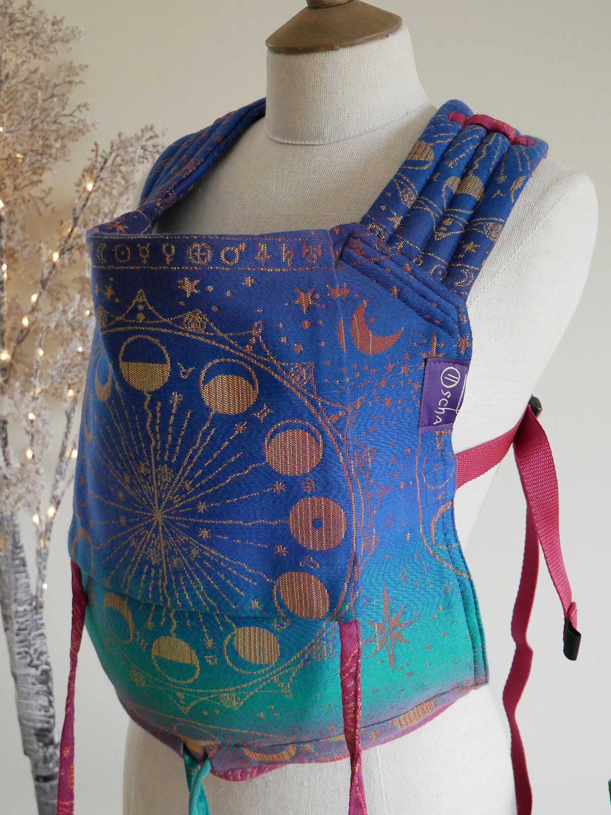 Blue baby carrier with celestial pattern on a mannequin against a neutral background