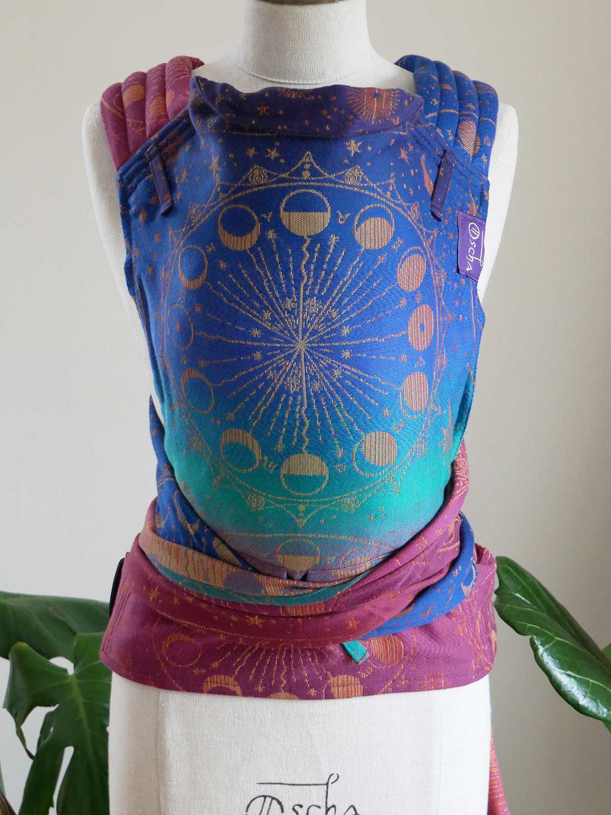 Colourful baby carrier with celestial design on a mannequin against a white background