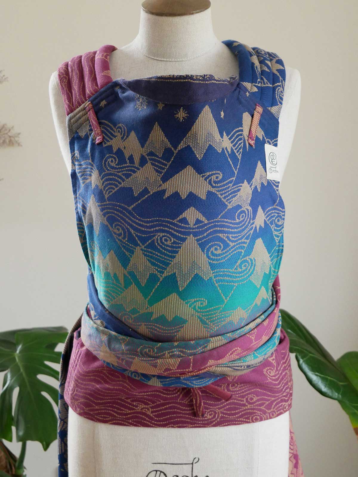 Baby carrier with mountain design on a mannequin against a neutral background