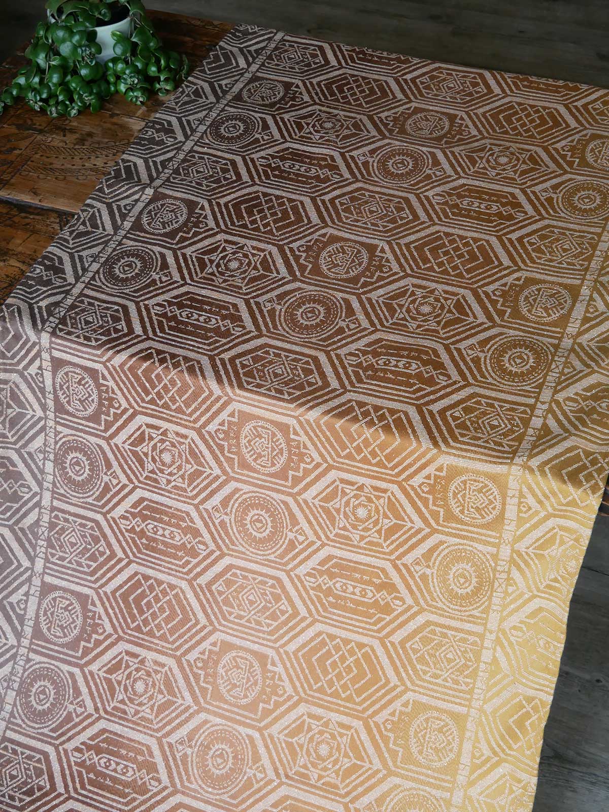 Hexagonal patterned fabric on a wooden table with a plant in the corner.