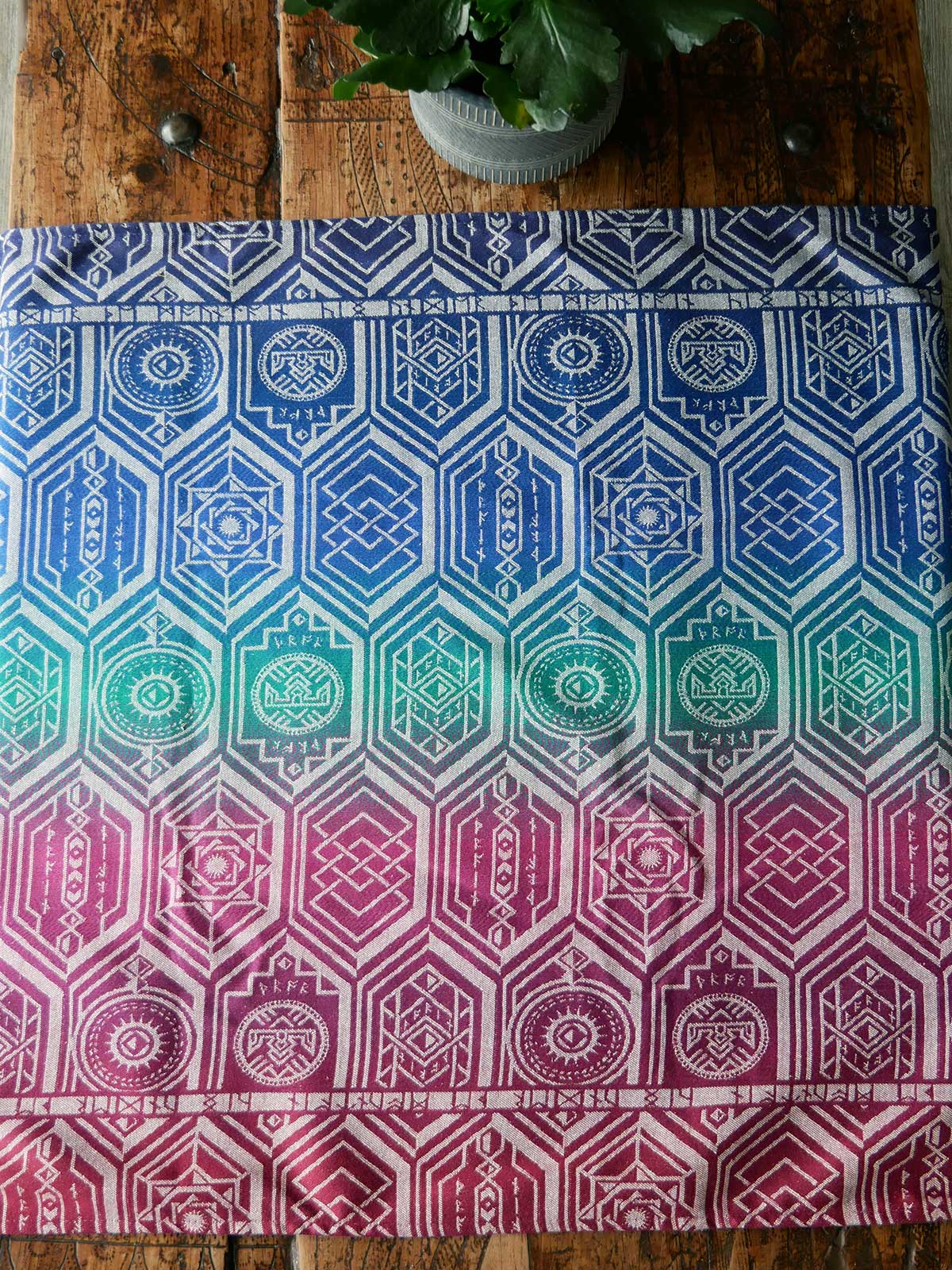Fabric laid on a wooden table in jewel tones with a repeating shield pattern.