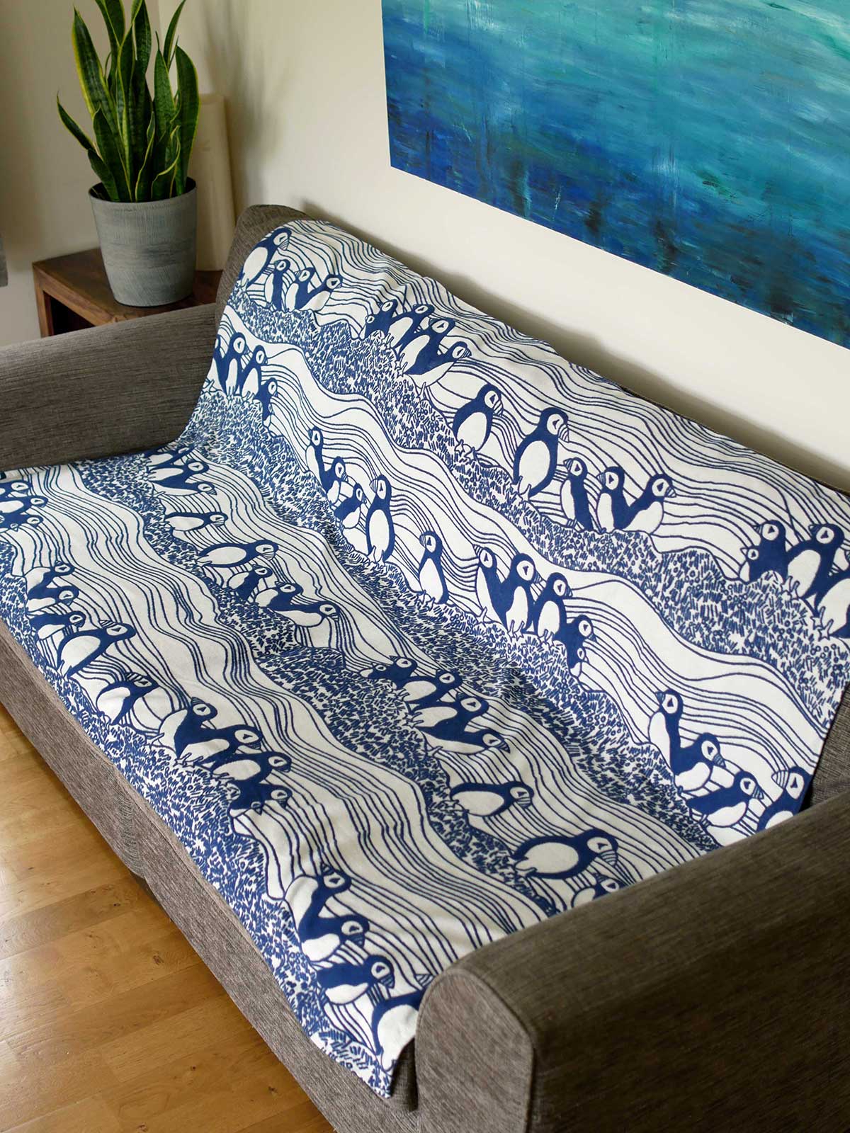 Lightweight blanket with puffin pattern laid over a sofa