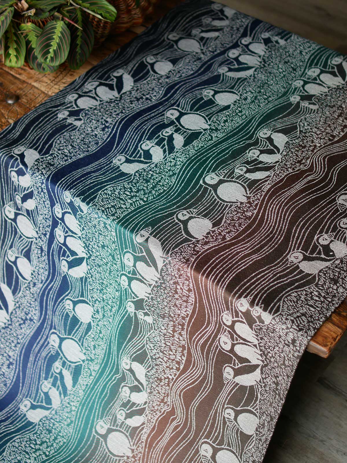 Blue, green and brown fabric with puffin design on a wooden table.