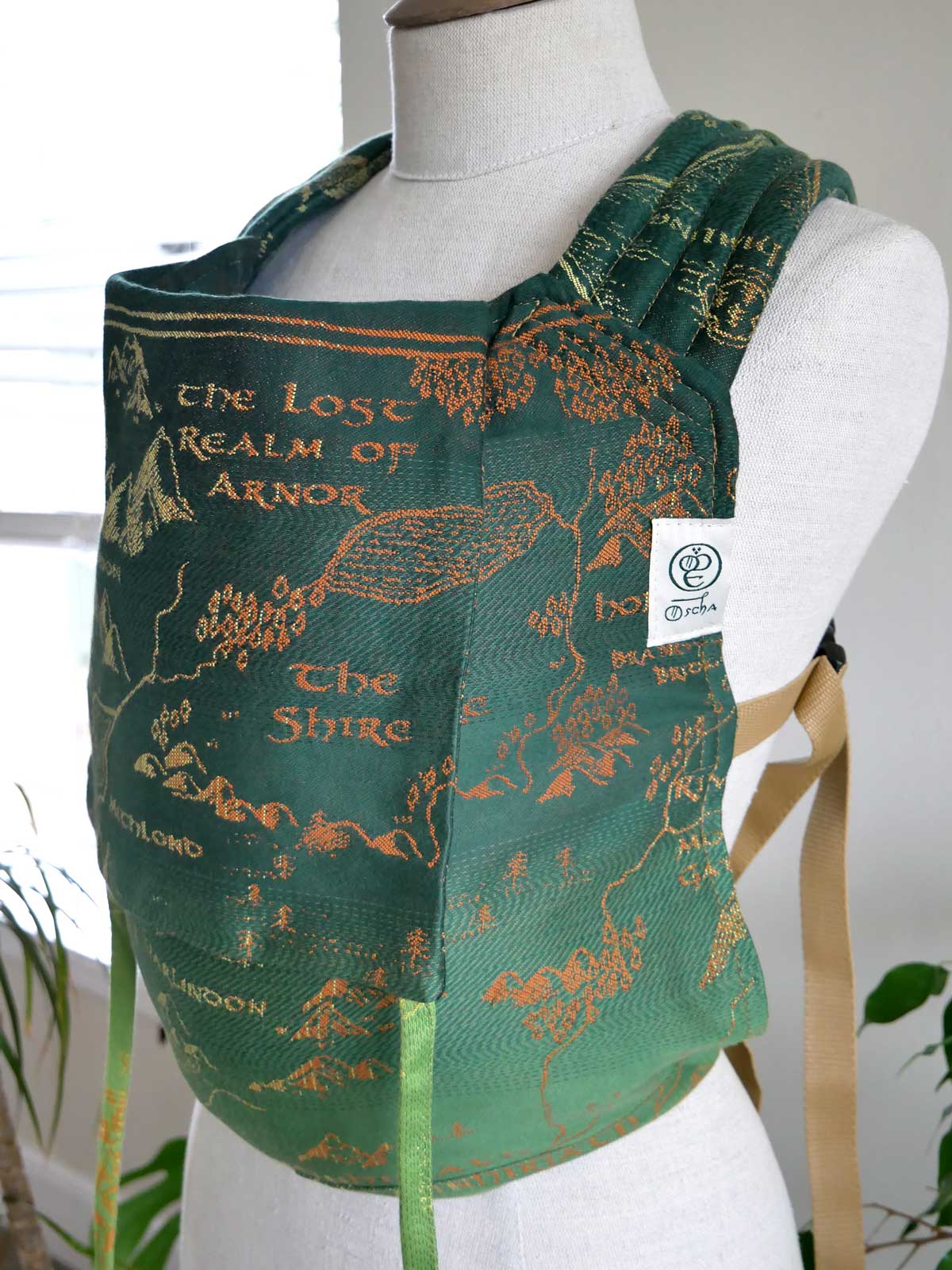 Green baby carrier with a map design on a mannequin