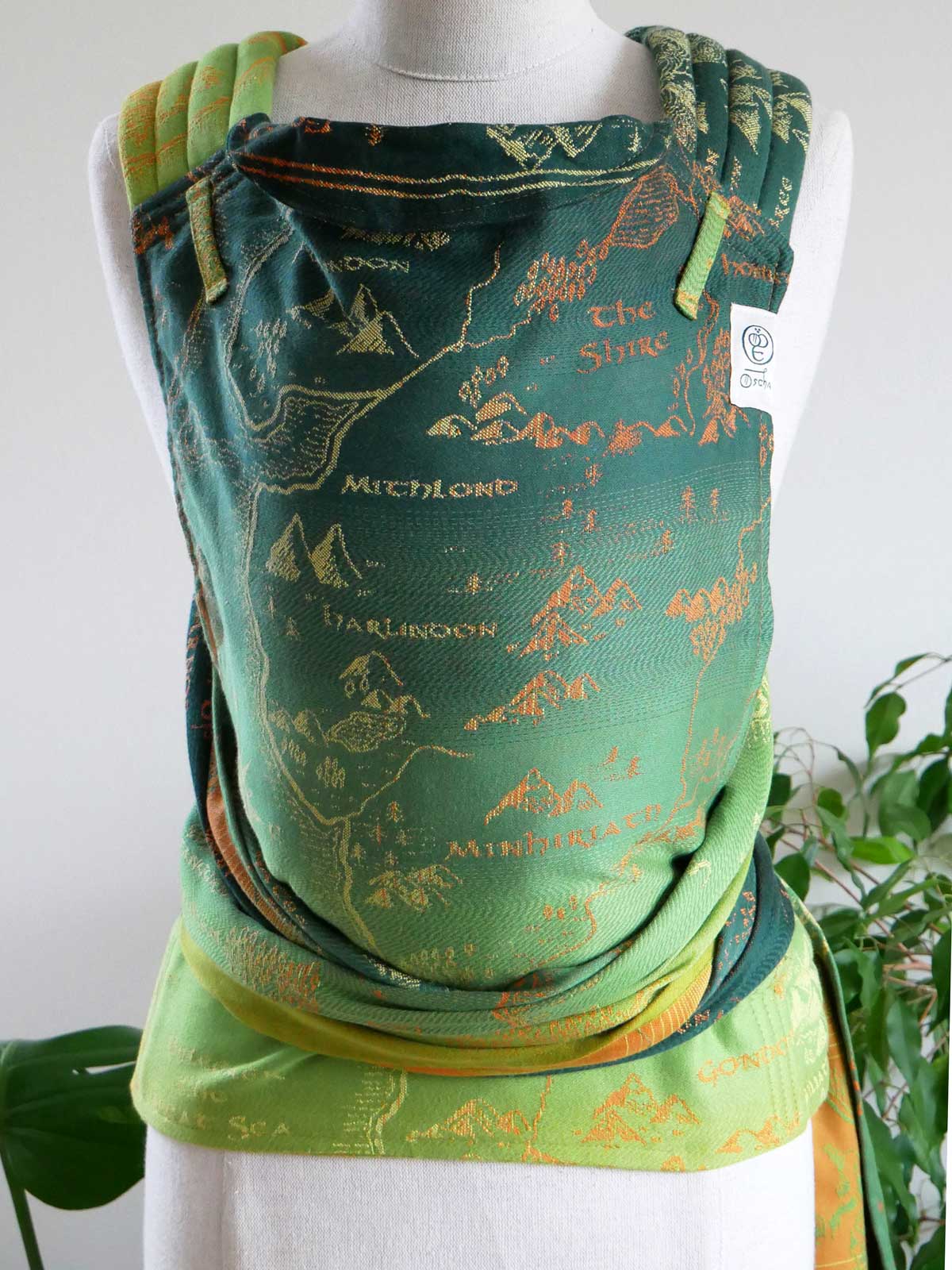 Green half-buckle baby carrier with a map design on a mannequin