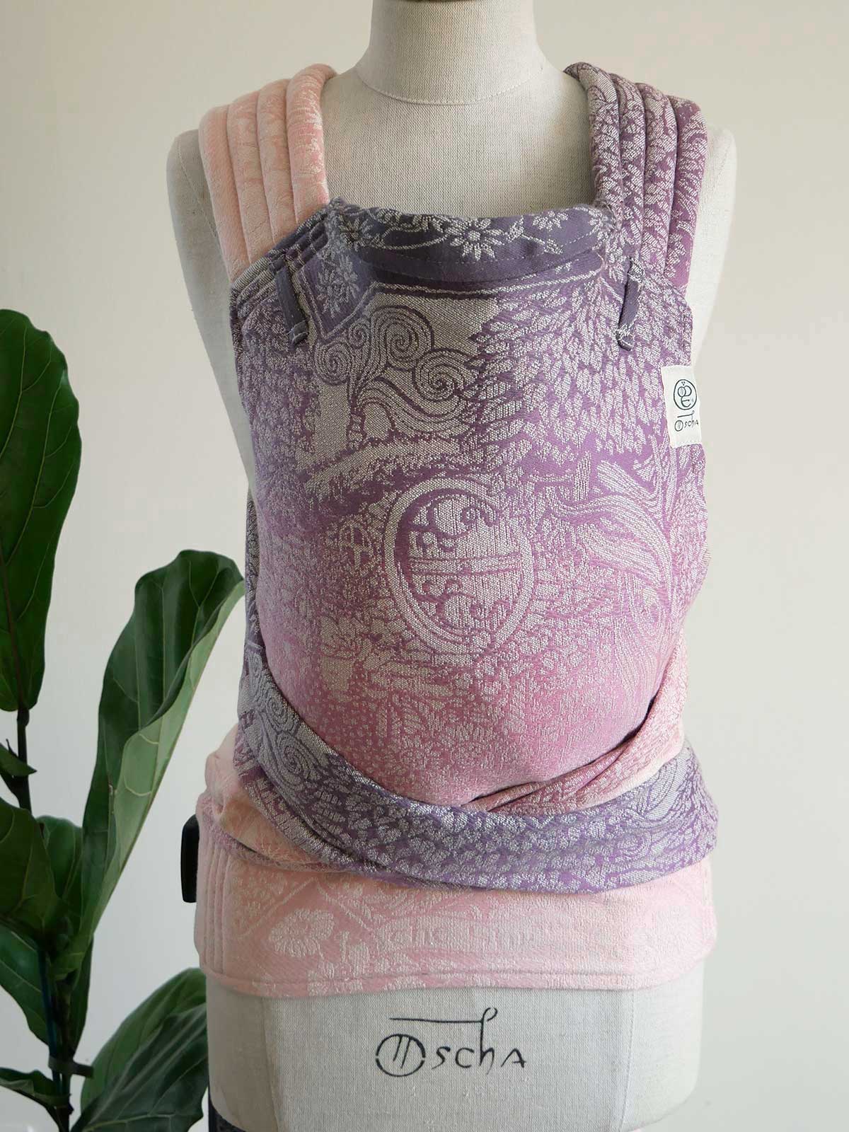 Baby carrier with purple and pink design on a mannequin against a white background