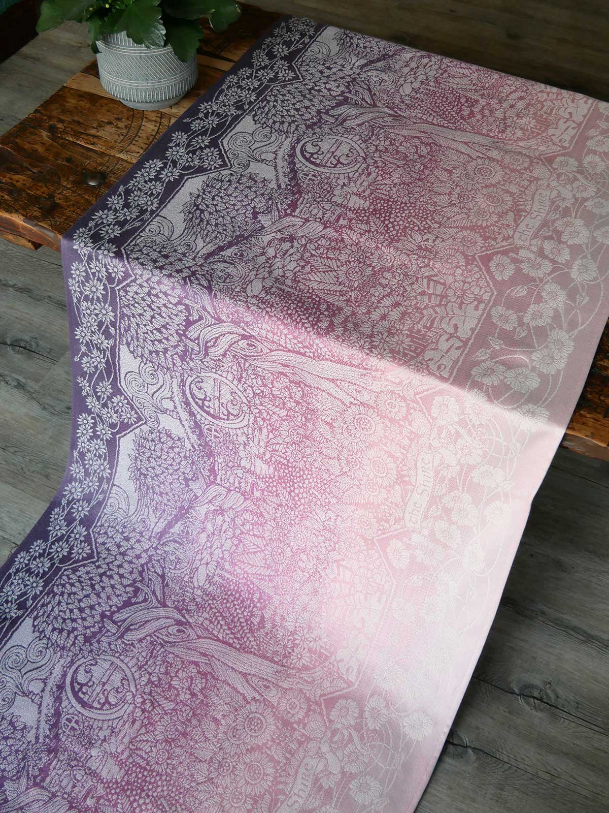 Patterned fabric with a gradient of purple to pink on a wooden surface.
