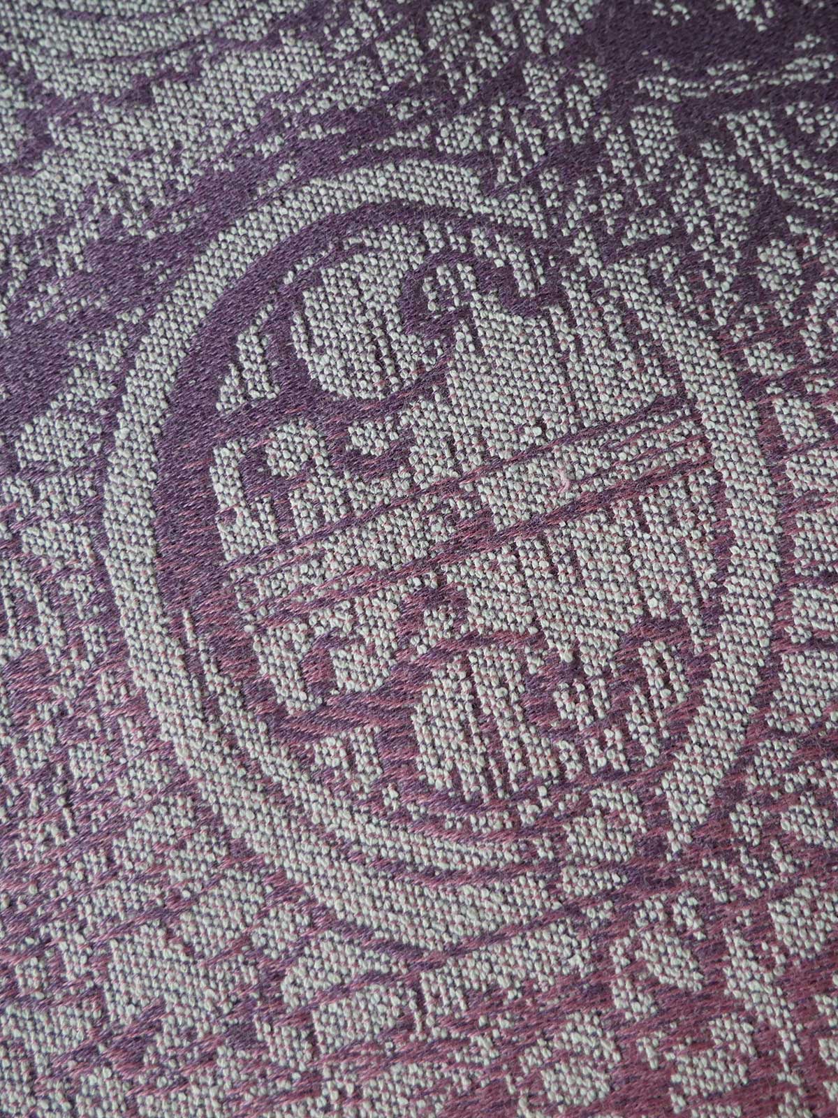 Close-up of a textured fabric with a purple pattern on a gray background