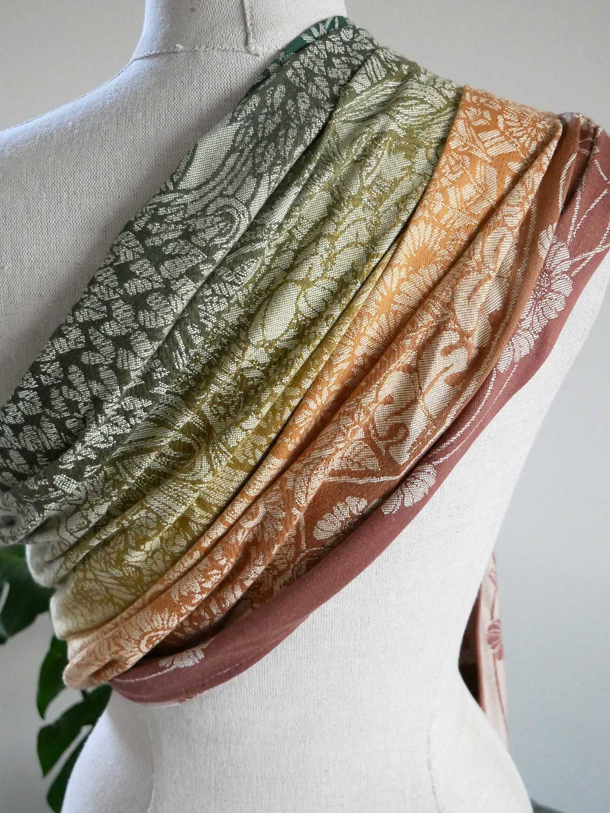 Mannequin wearing a ring sling in green, orange, and brown.