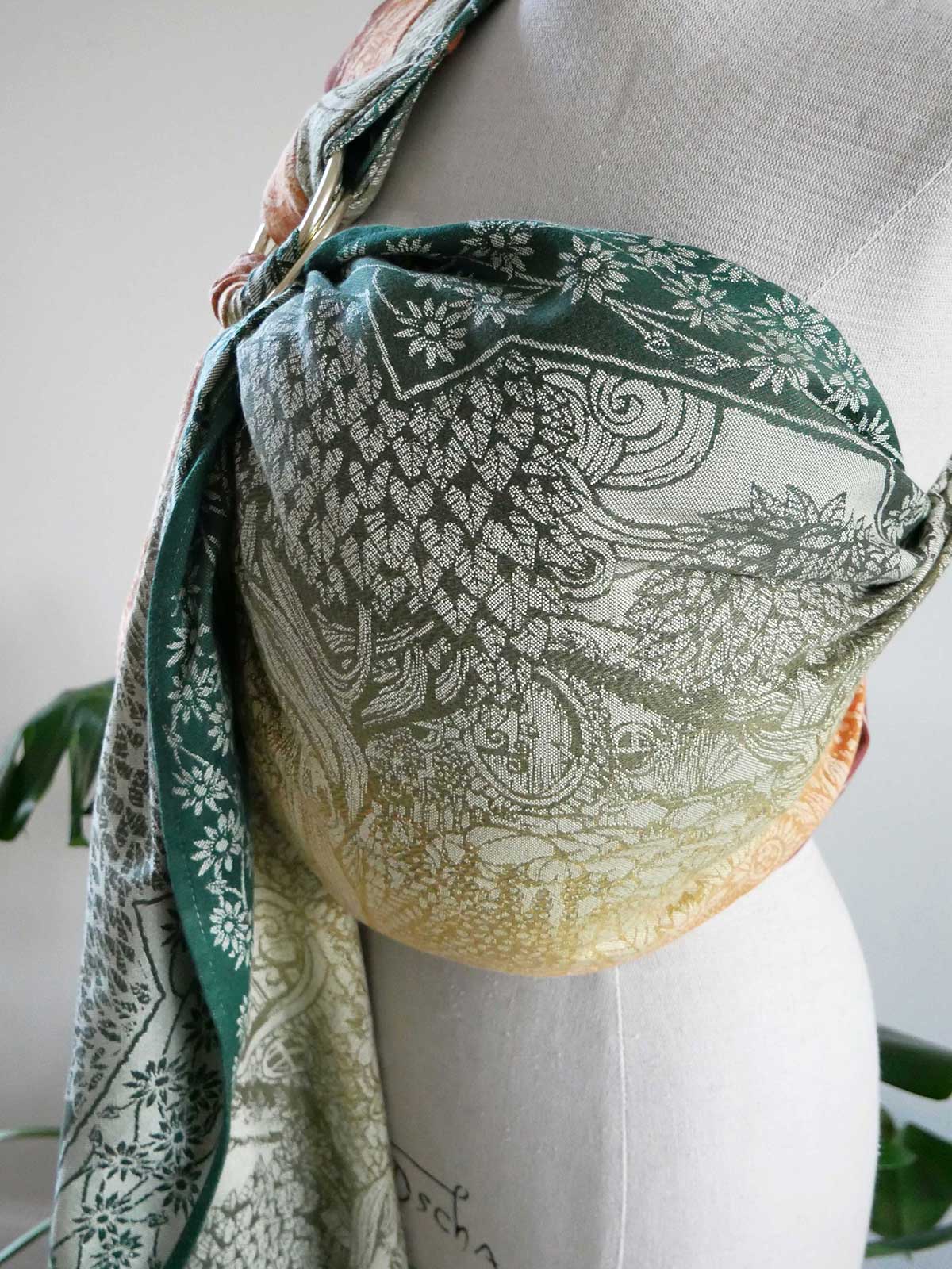 Green and white ring sling draped over a mannequin