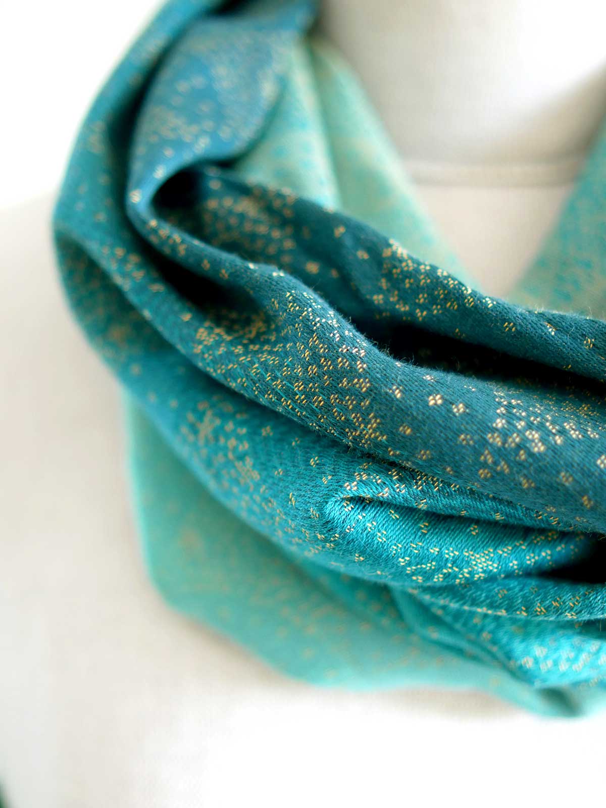 Close up of cowl with teal fade and gold details on mannequin