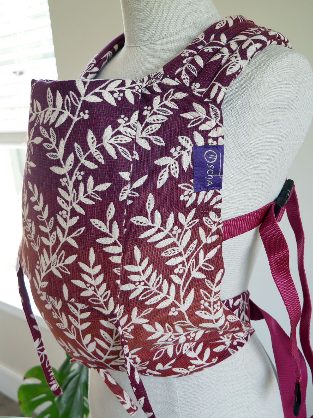 Willow Herbstlaub Bairn Baby Carrier with leaf pattern on a mannequin against a white background