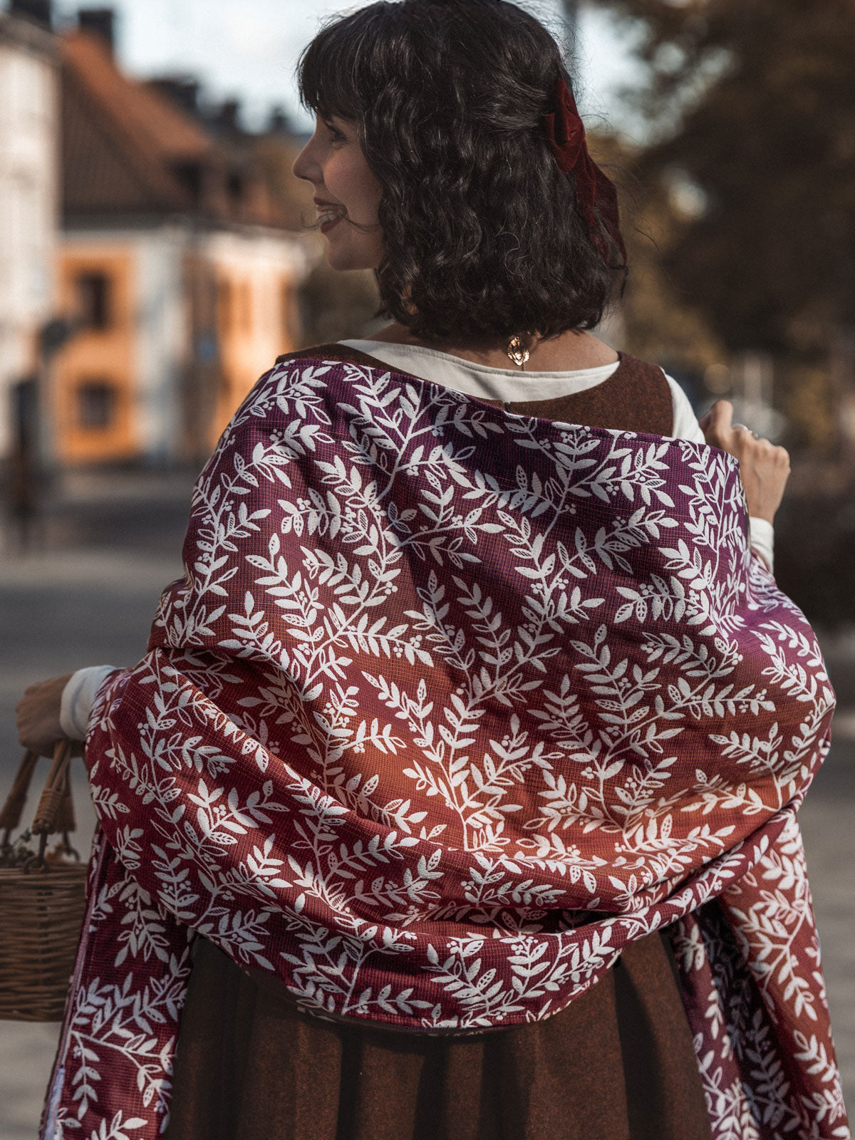 Woman wearing a Willow Herbstlaub Shawl outdoors with blurred background