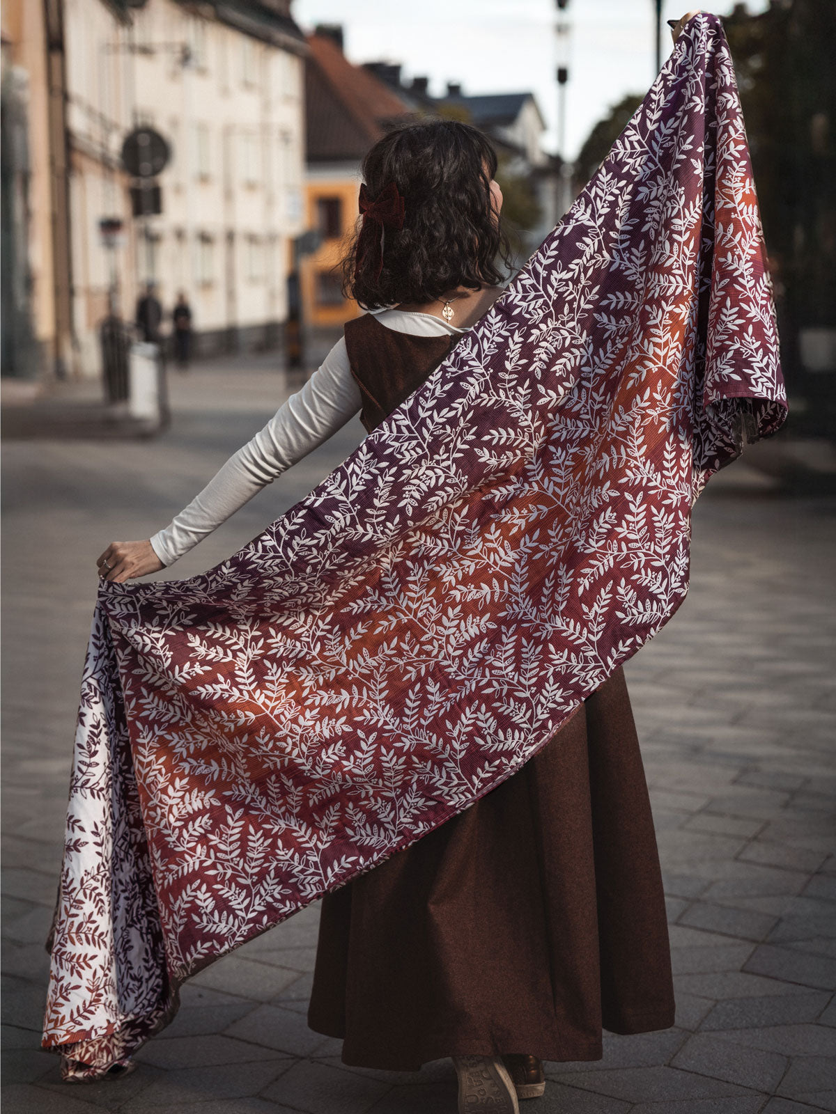Woman holding a large floral-patterned woven wrap on a street