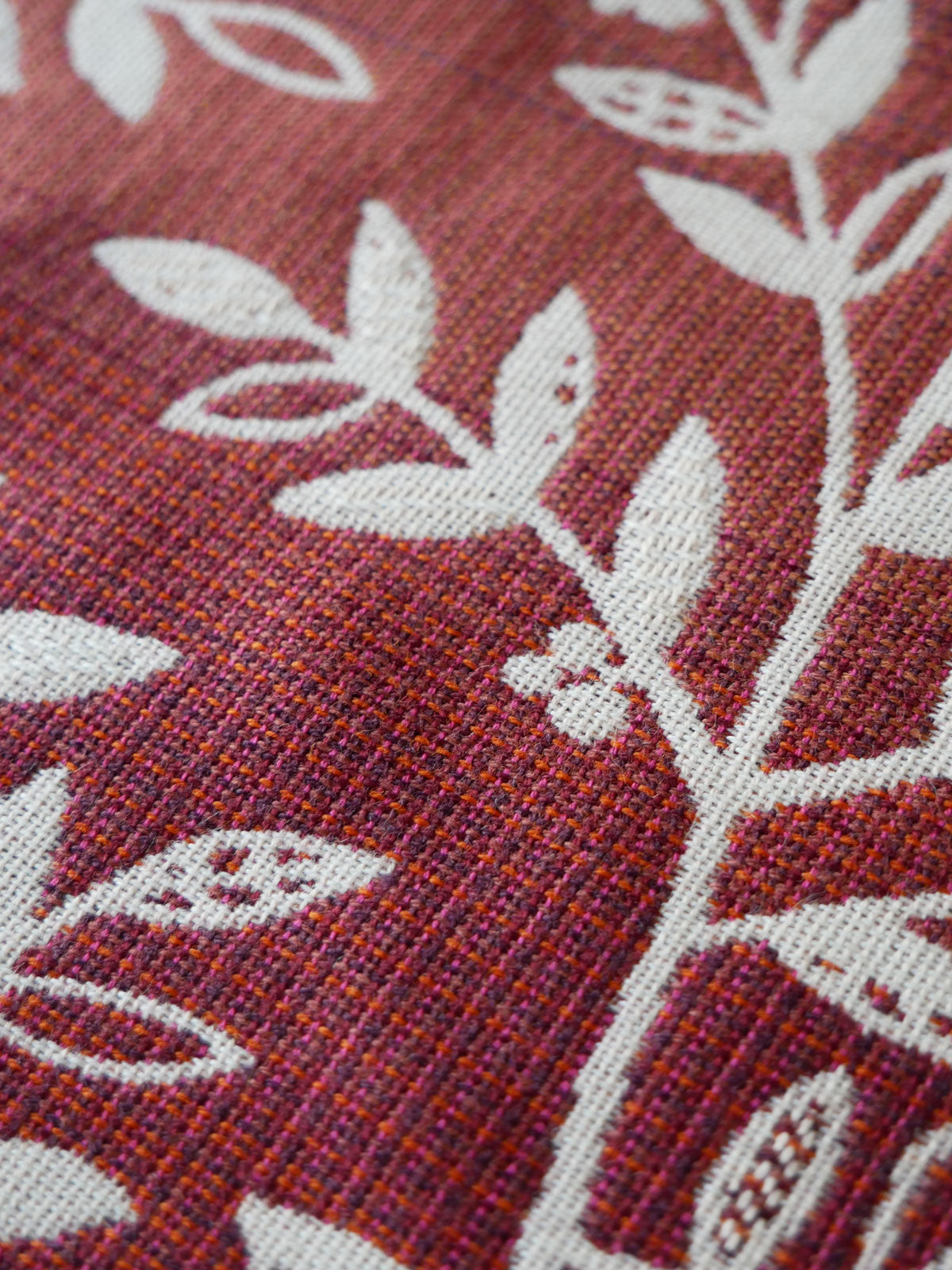 Close-up of a fabric with white leaf patterns on a burgundy background