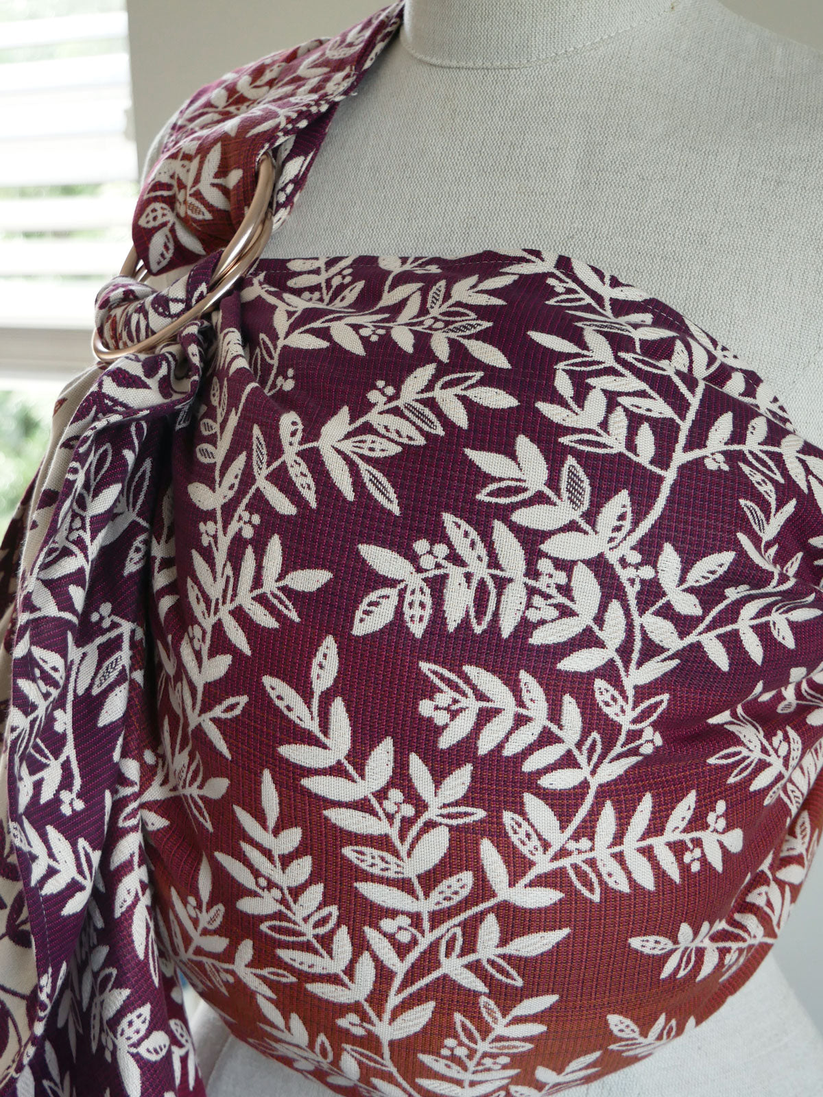 Burgundy purple fabric with white leaf pattern draped over a mannequin
