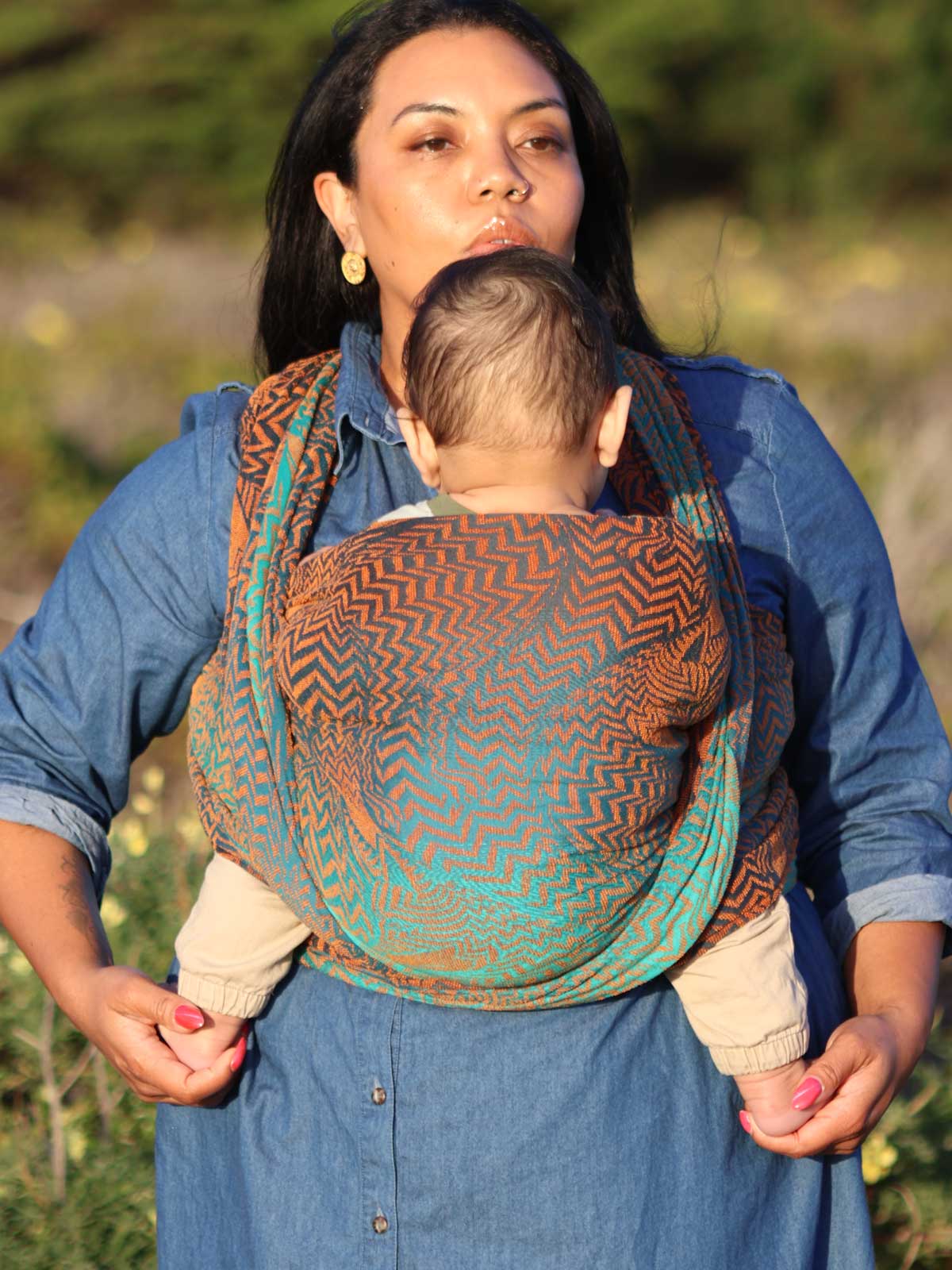 Woman carrying baby in a Fox pattern wrap.