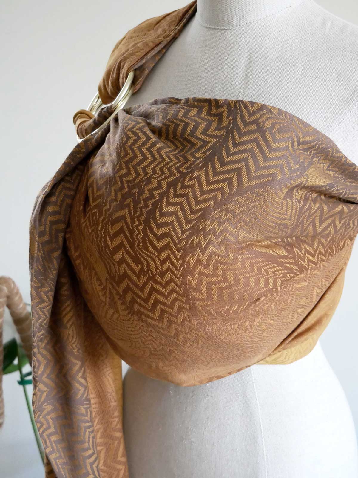 Brown patterned ring sling draped over a mannequin on a white background