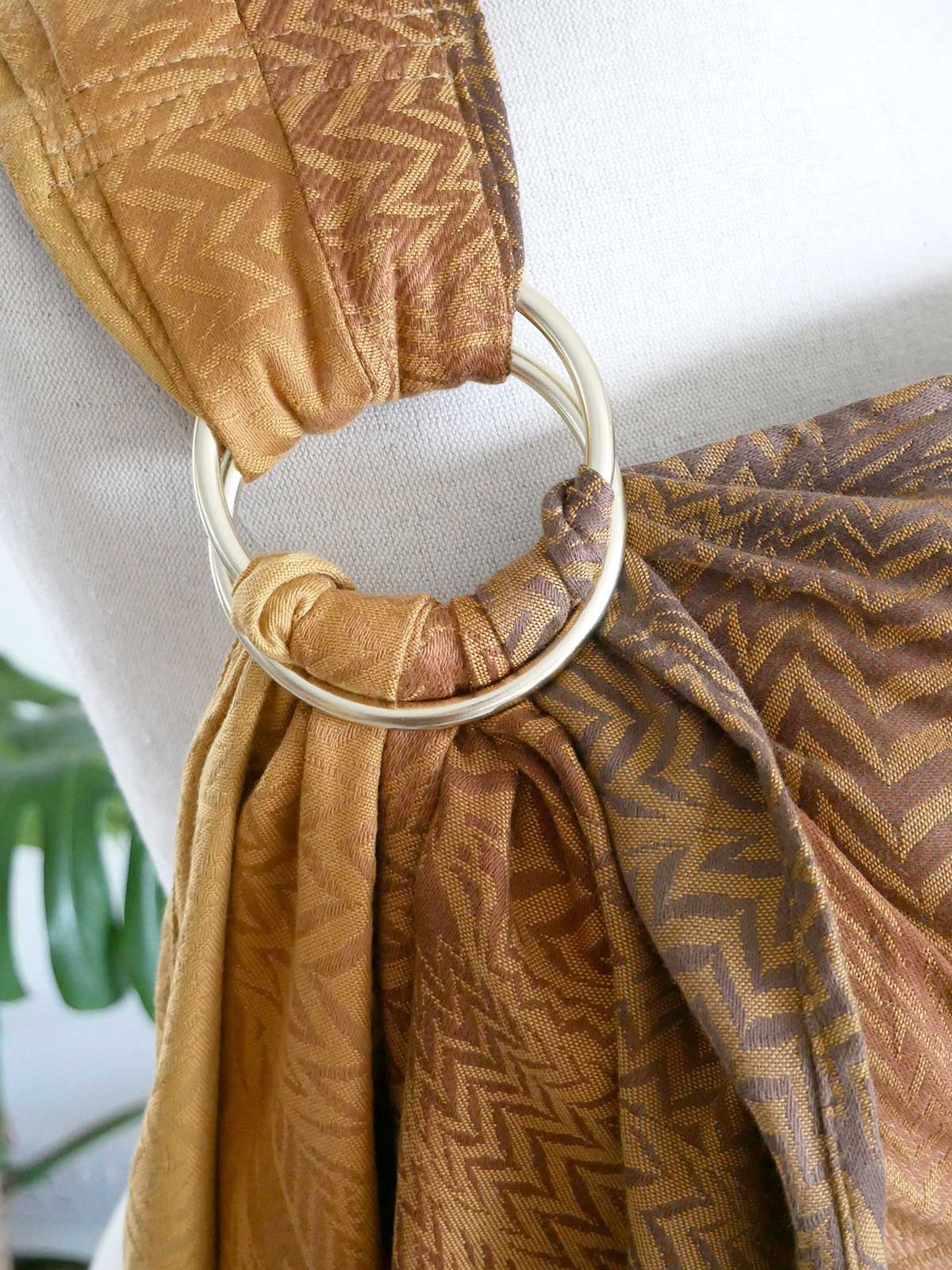 Brown patterned fabric with a gold ring on a white background