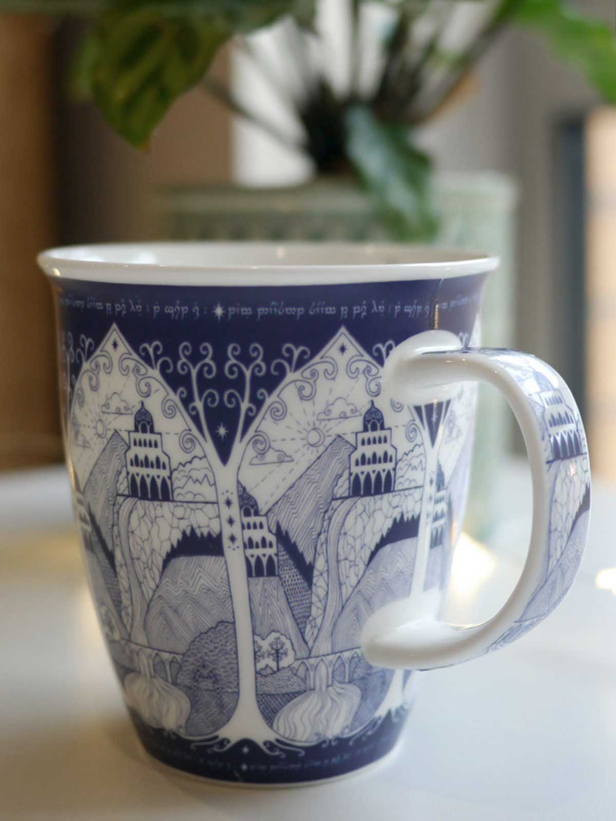 A large, blue and white, Middle-earth themed ceramic mug with Elvish text and Tolkien-inspired illustrative style designs.