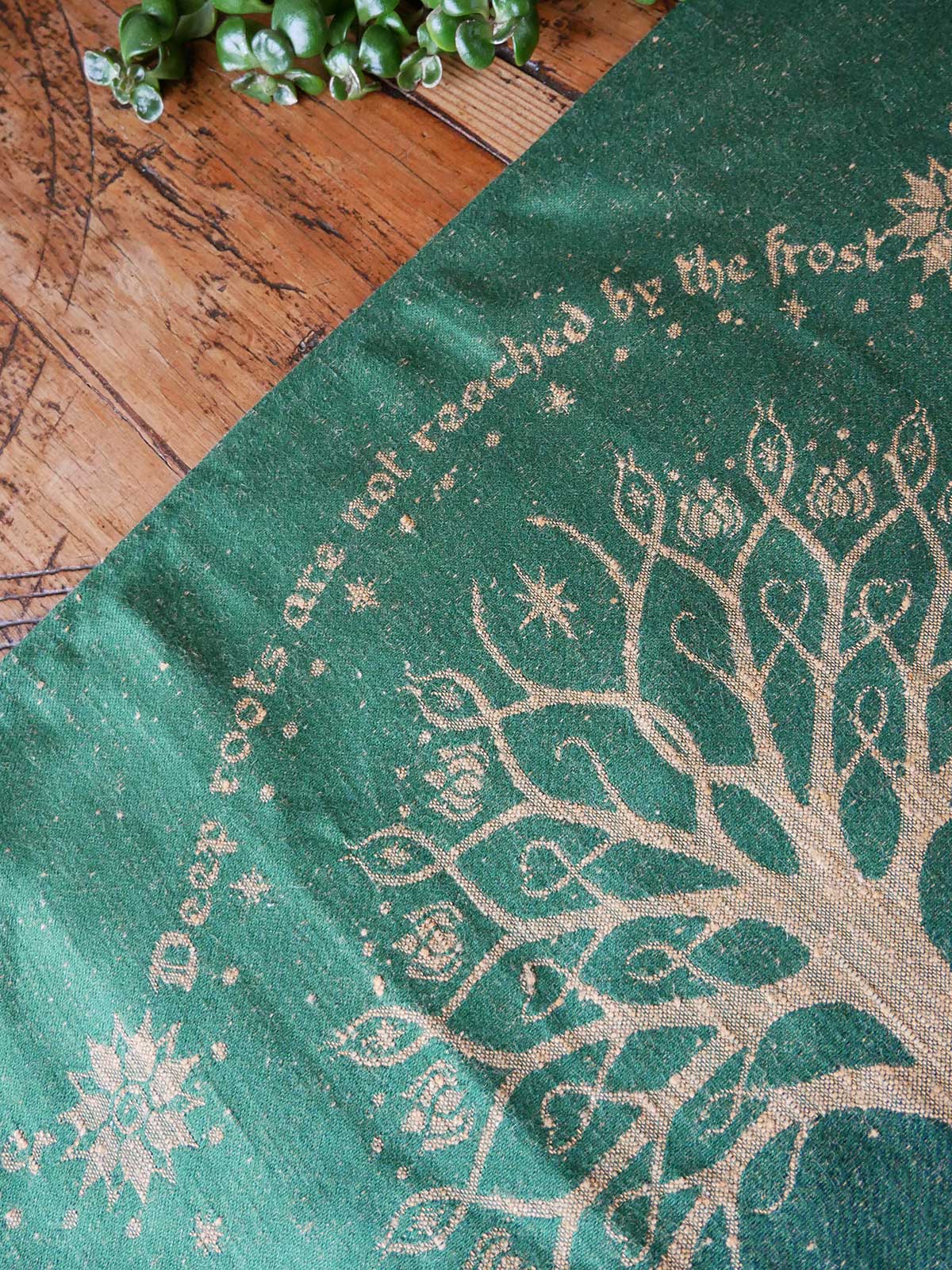 Green fabric with tree design and text on a wooden surface