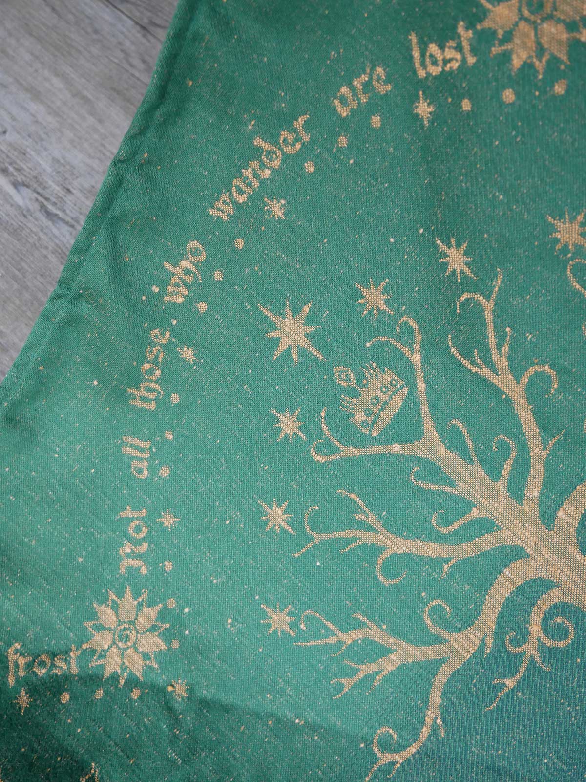 Green fabric with gold tree design and text on a wooden surface