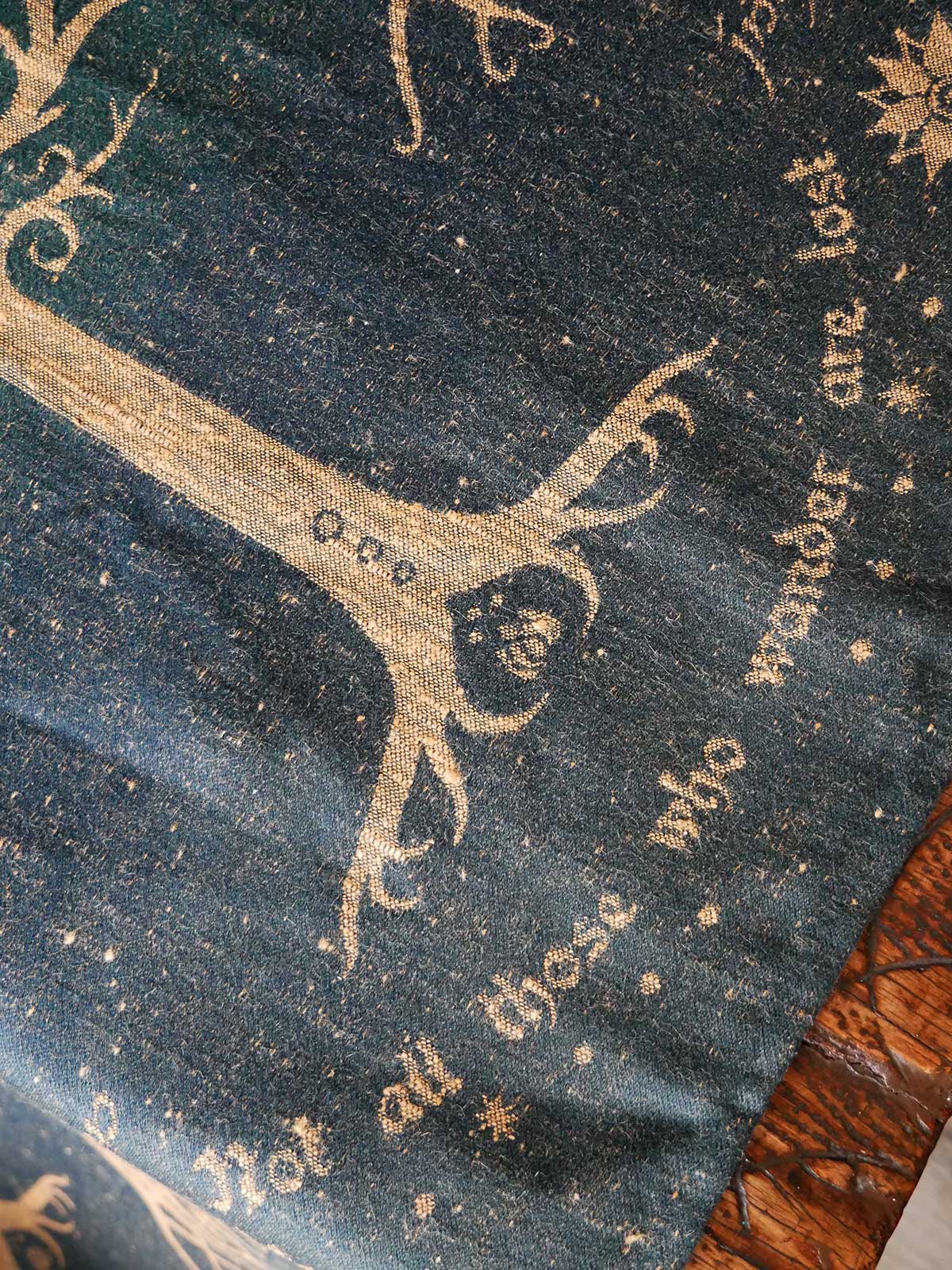 Decorative fabric with gold embroidery of a tree and text on a dark background